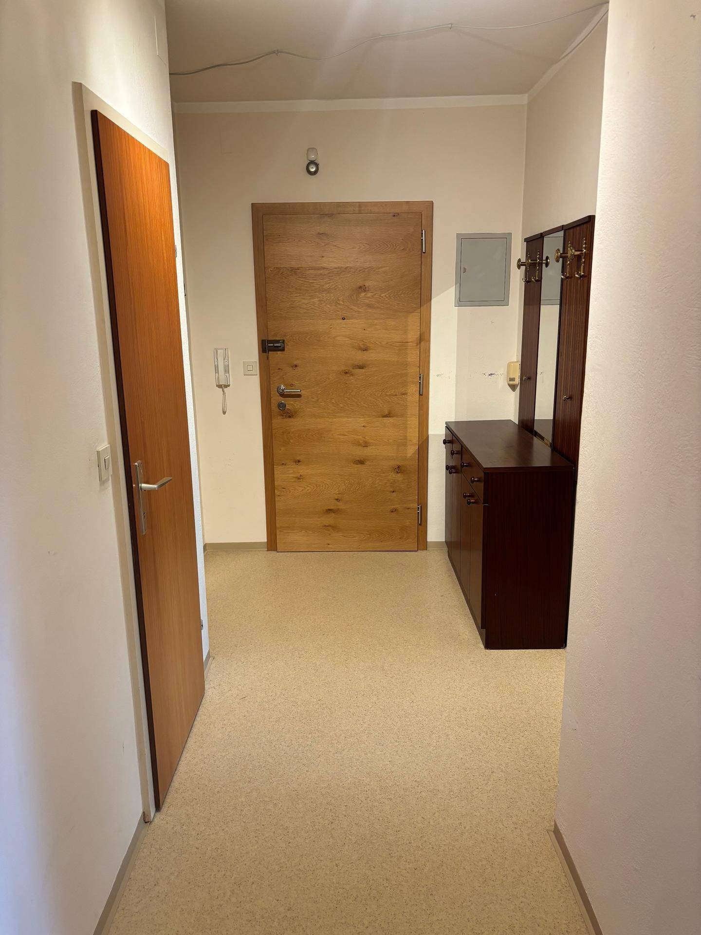 Eingangsbereich mit Holztür, Garderobe und Spiegel, der einen freundlichen Empfang bietet.