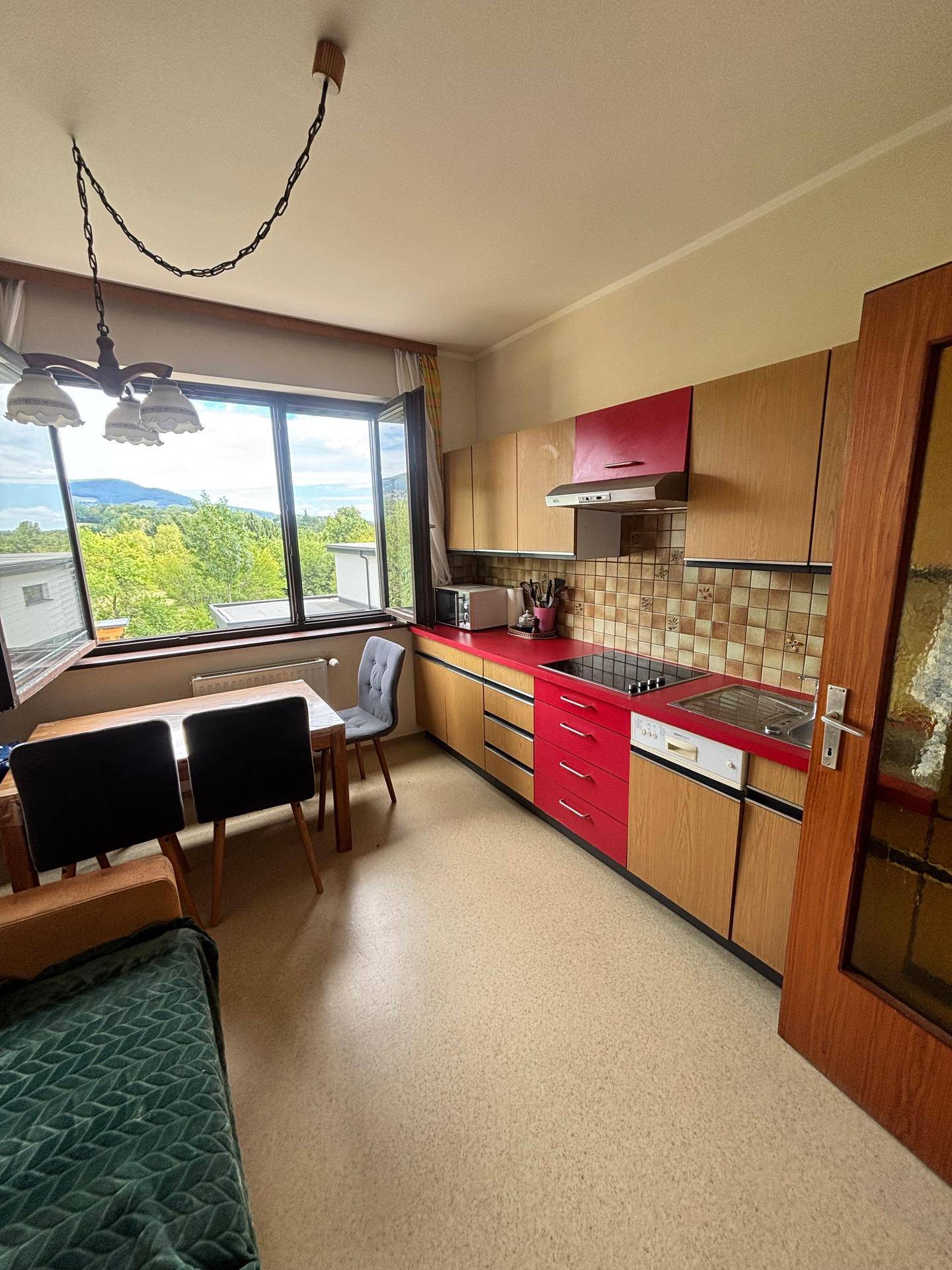 Küche mit Essbereich, Holzschränken und roten Akzenten, bietet einen schönen Ausblick.
