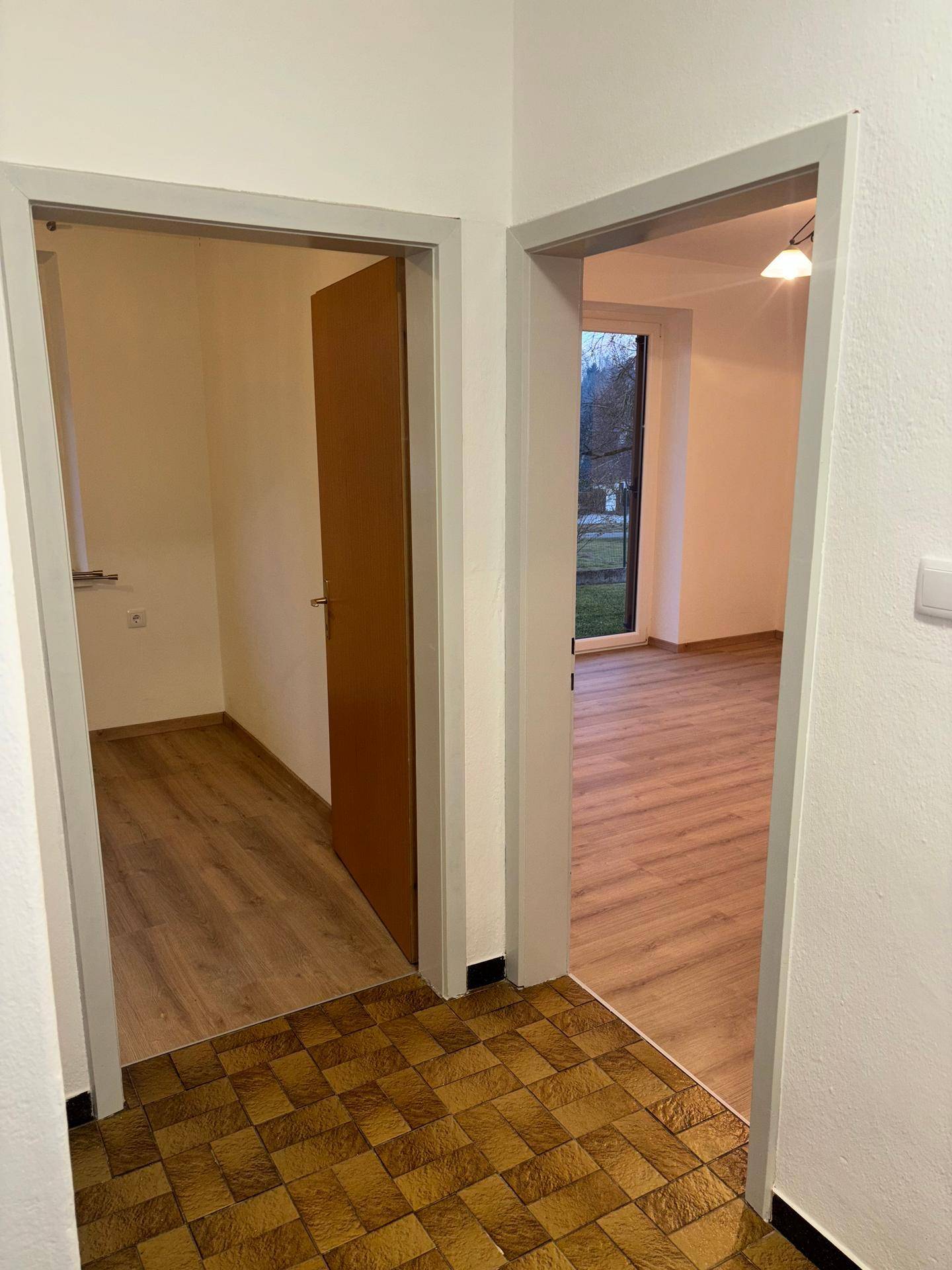 Flur mit gefliestem Boden und Zugängen zu weiteren Räumen mit Laminatboden.