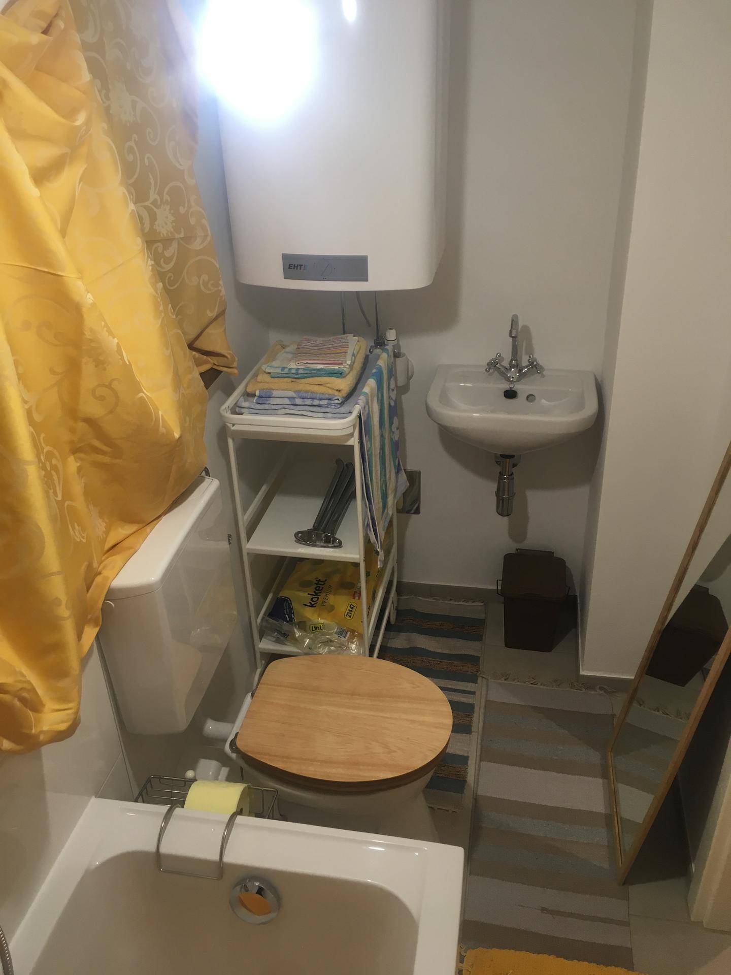 Kleines Badezimmer mit Toilette, Waschbecken und Warmwasserboiler.