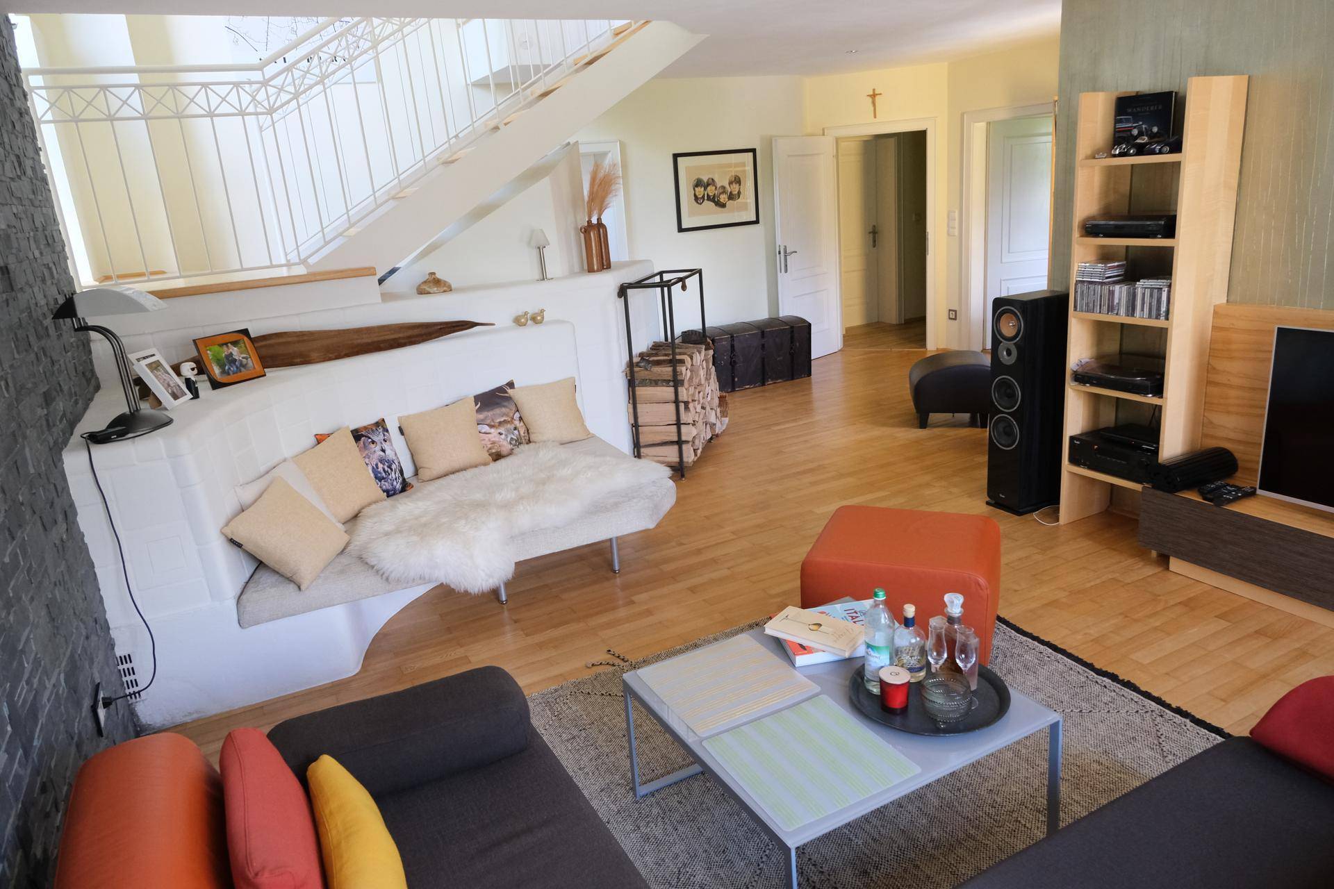 Helles Wohnzimmer mit Holzfußboden, integrierter Sitzbank und offener Treppe.