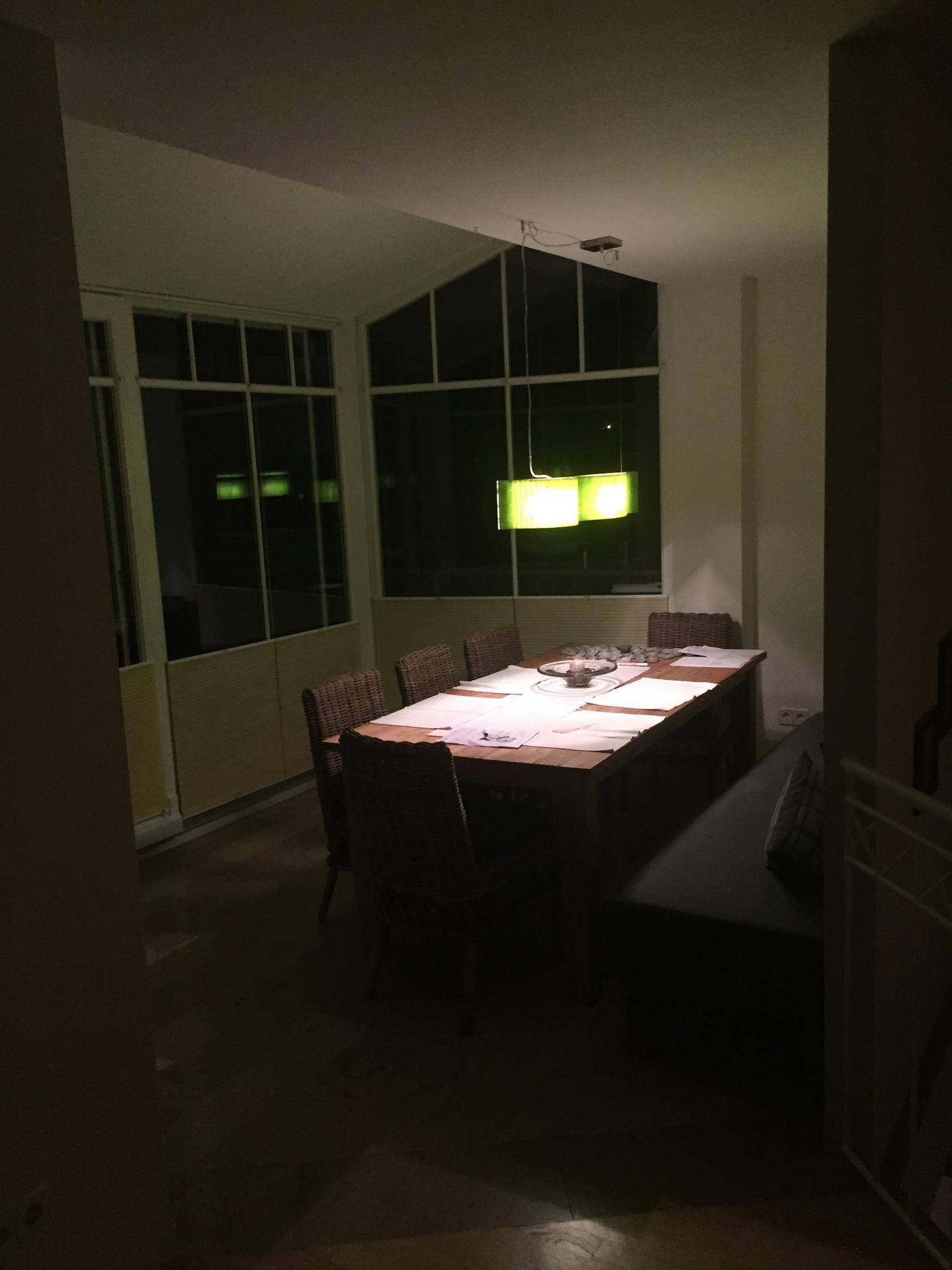 Gemütlicher Essbereich am Abend mit großem Holztisch und modernen Hängelampen.