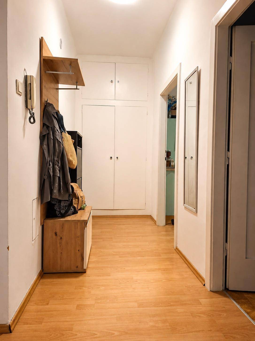 Heller Flur mit praktischer Garderobe, Holzmöbeln und strapazierfähigem Laminatboden.