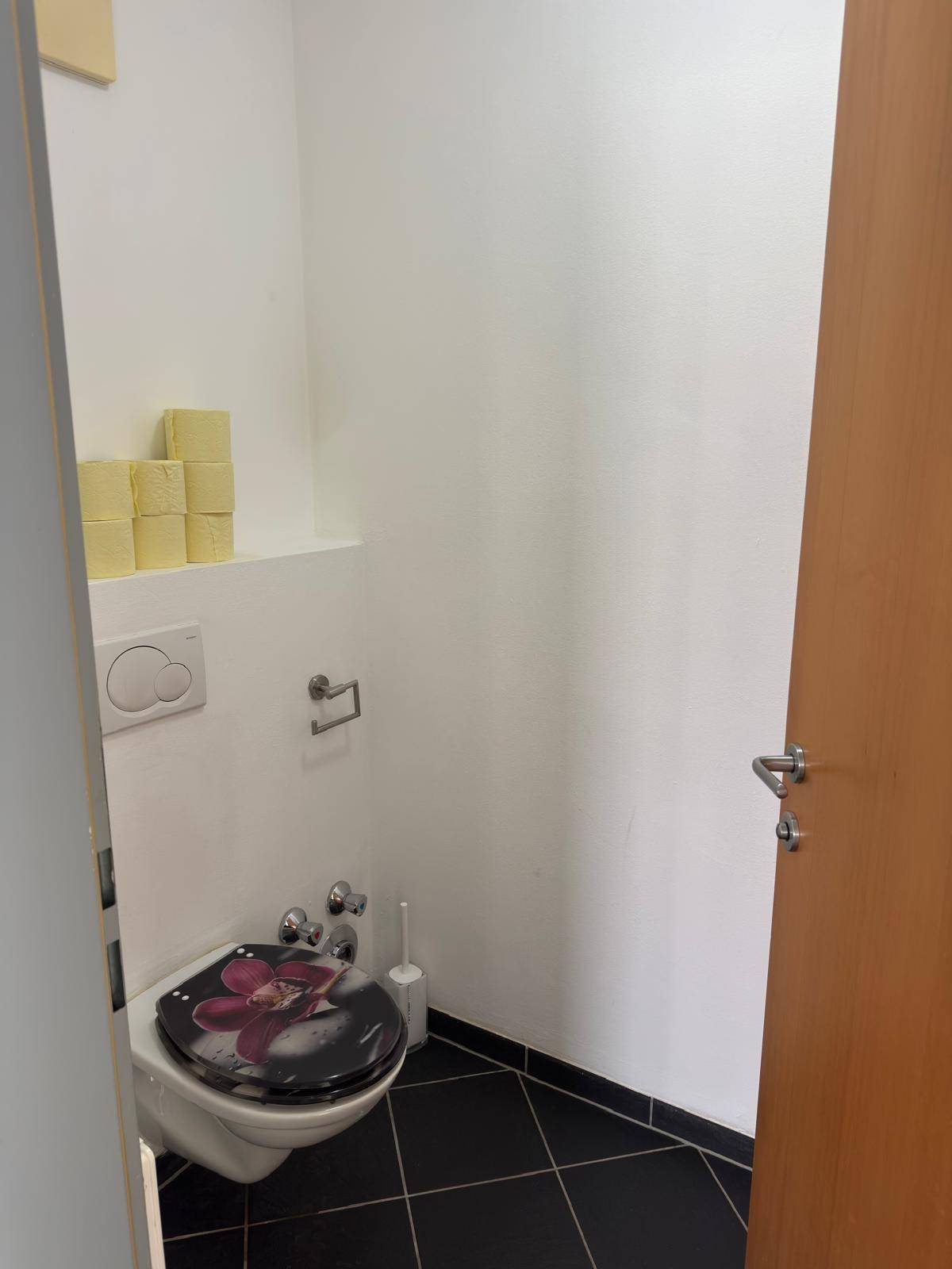 Separates Gäste-WC mit Toilette und dunklen Bodenfliesen, praktisch und funktional.