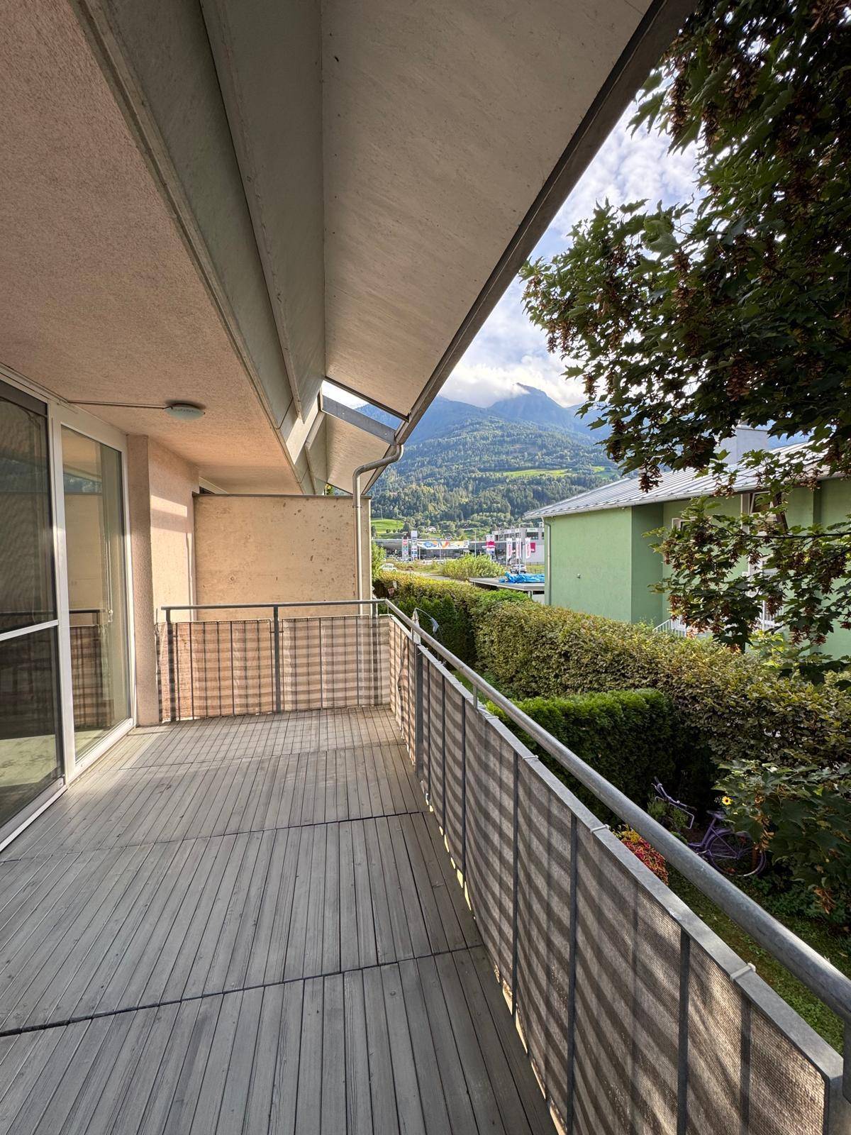 Geräumiger Balkon mit Holzboden und schöner Aussicht auf die umliegende Berglandschaft.