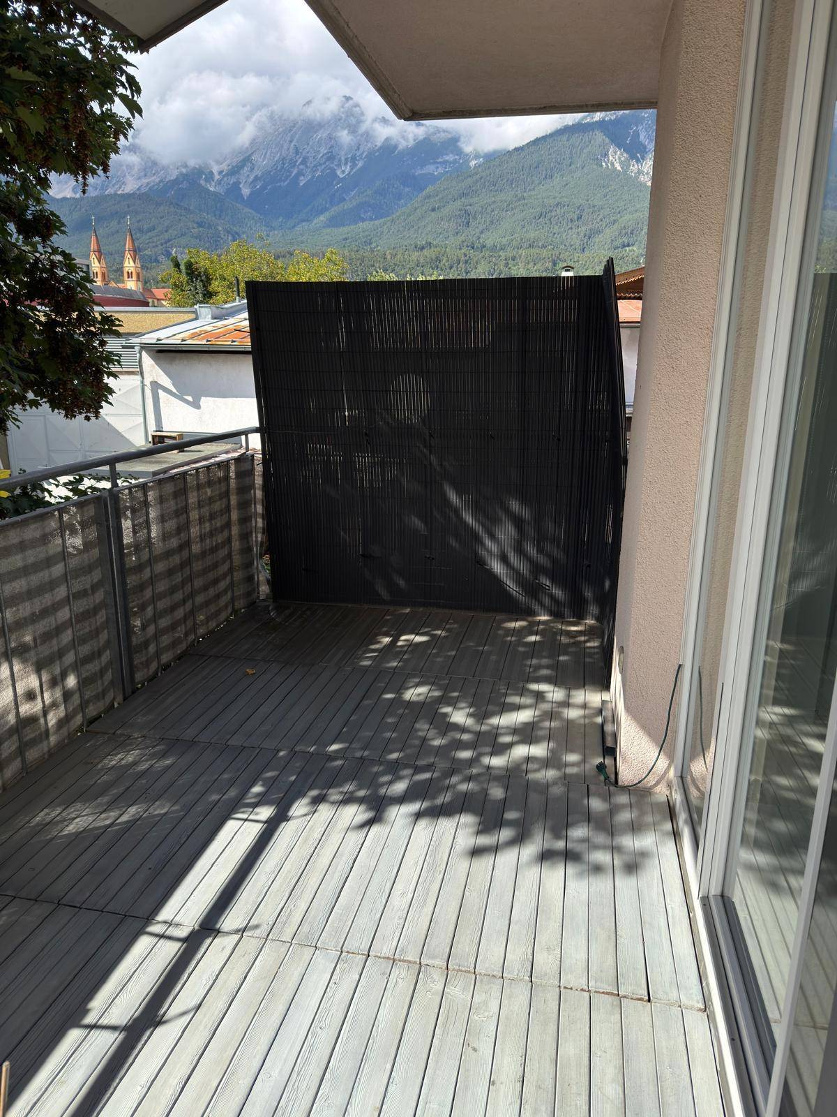 Balkon mit Holzboden und Sichtschutz, bietet einen schönen Blick auf die Berge und die Stadt.