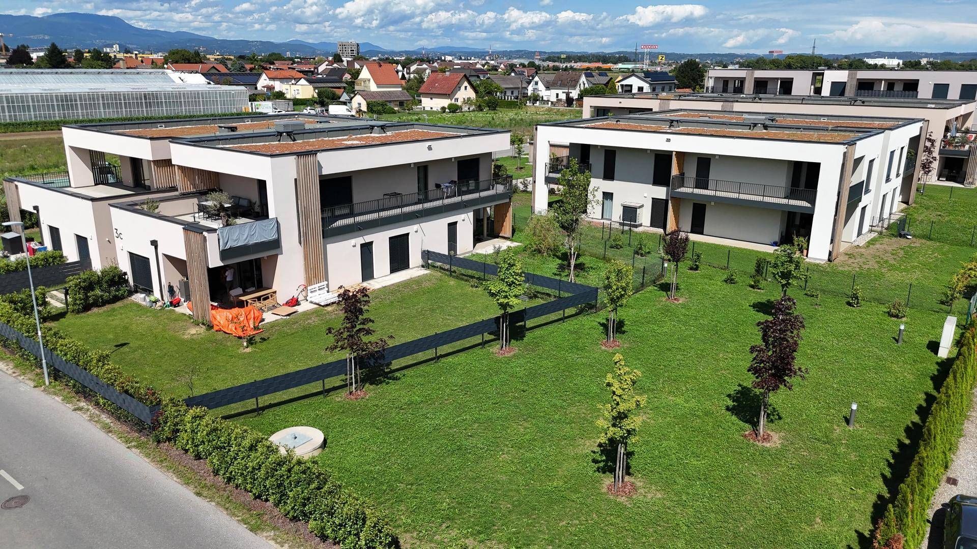 Übersicht der modernen Wohnanlage mit viel Grün und umliegenden Feldern.