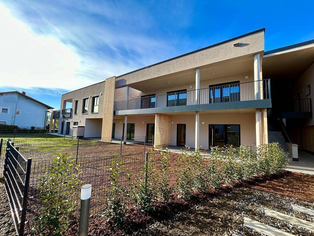 Rückansicht eines modernen Gebäudes mit Balkonen und Terrassen im Erdgeschoss.