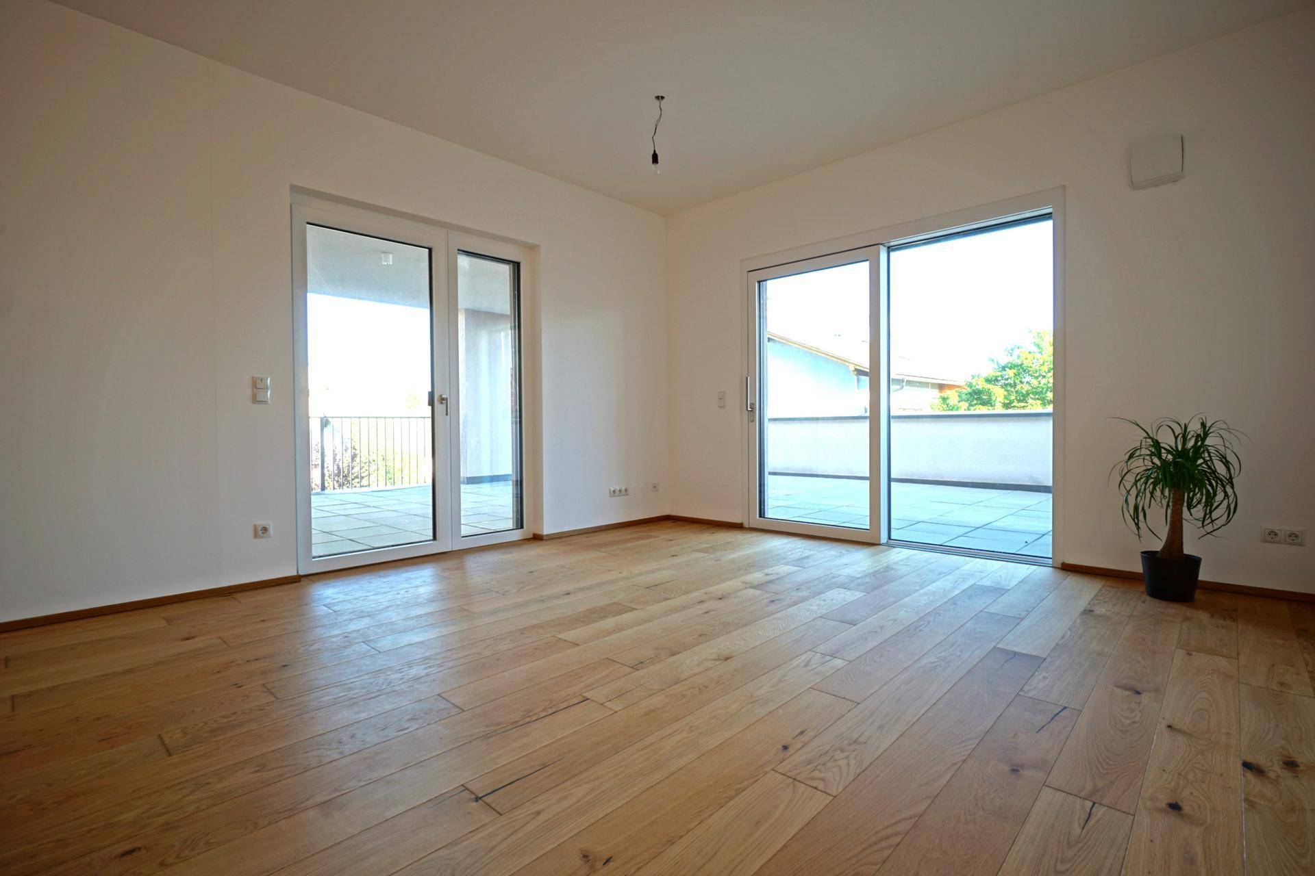 Helles Wohnzimmer mit Holzboden und Zugang zu einer großen Terrasse.