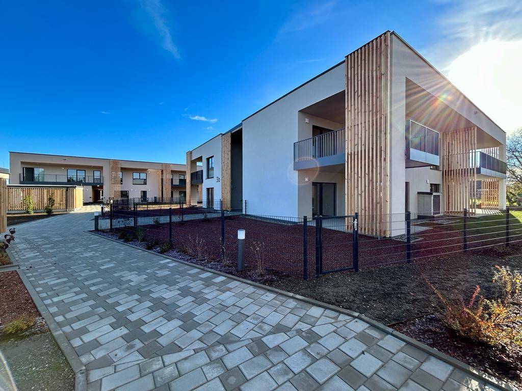 Moderne Gebäudefassade mit Holzverkleidung und Balkonen unter blauem Himmel.