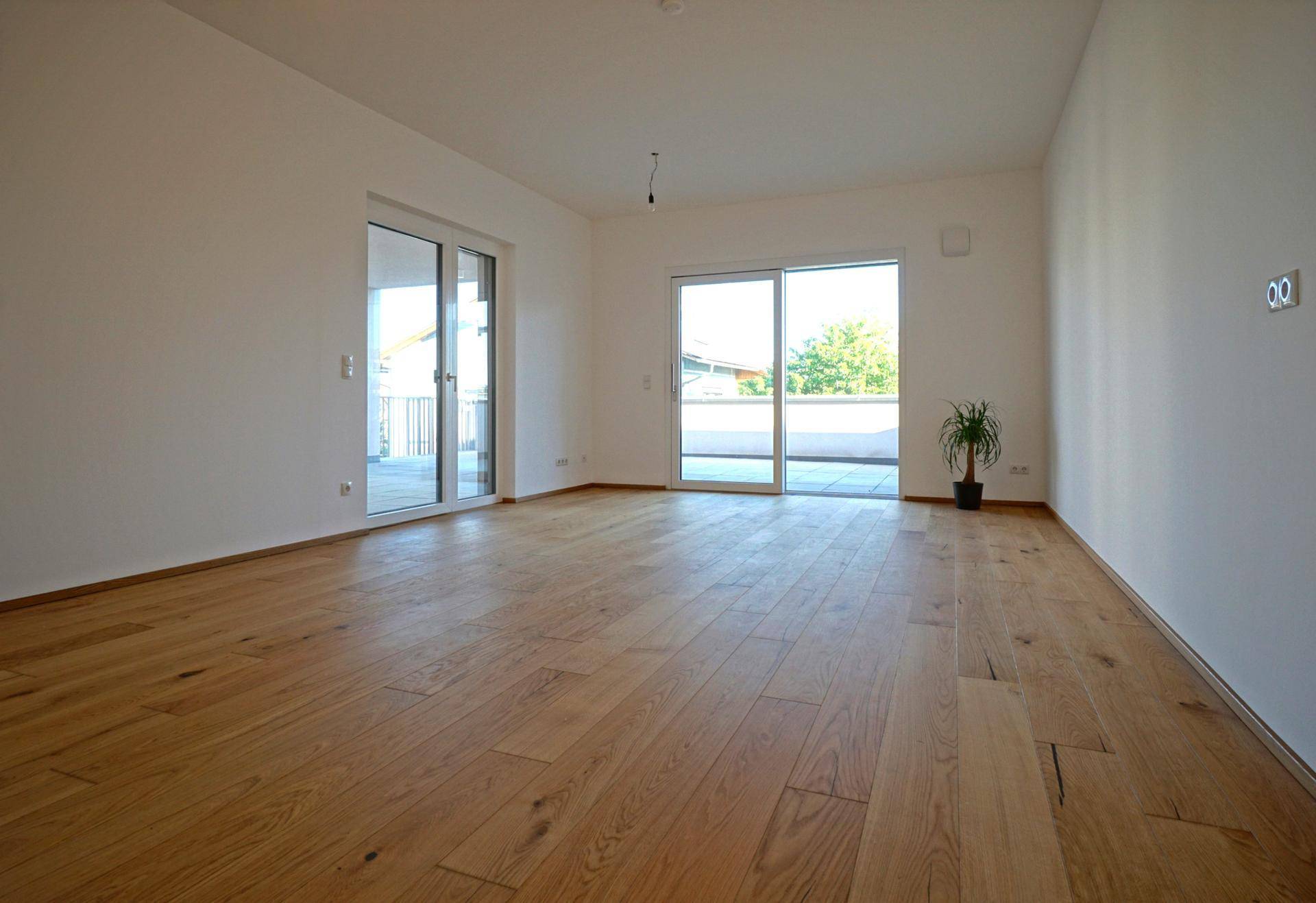 Geräumiges Wohnzimmer mit Eichenparkett und großen Schiebetüren zur Terrasse.
