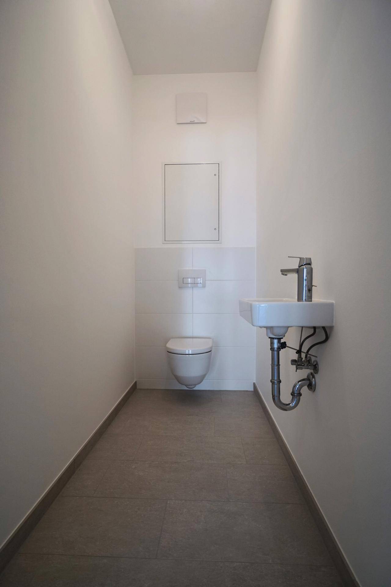 Modernes Gäste-WC mit wandhängender Toilette und kleinem Waschbecken.