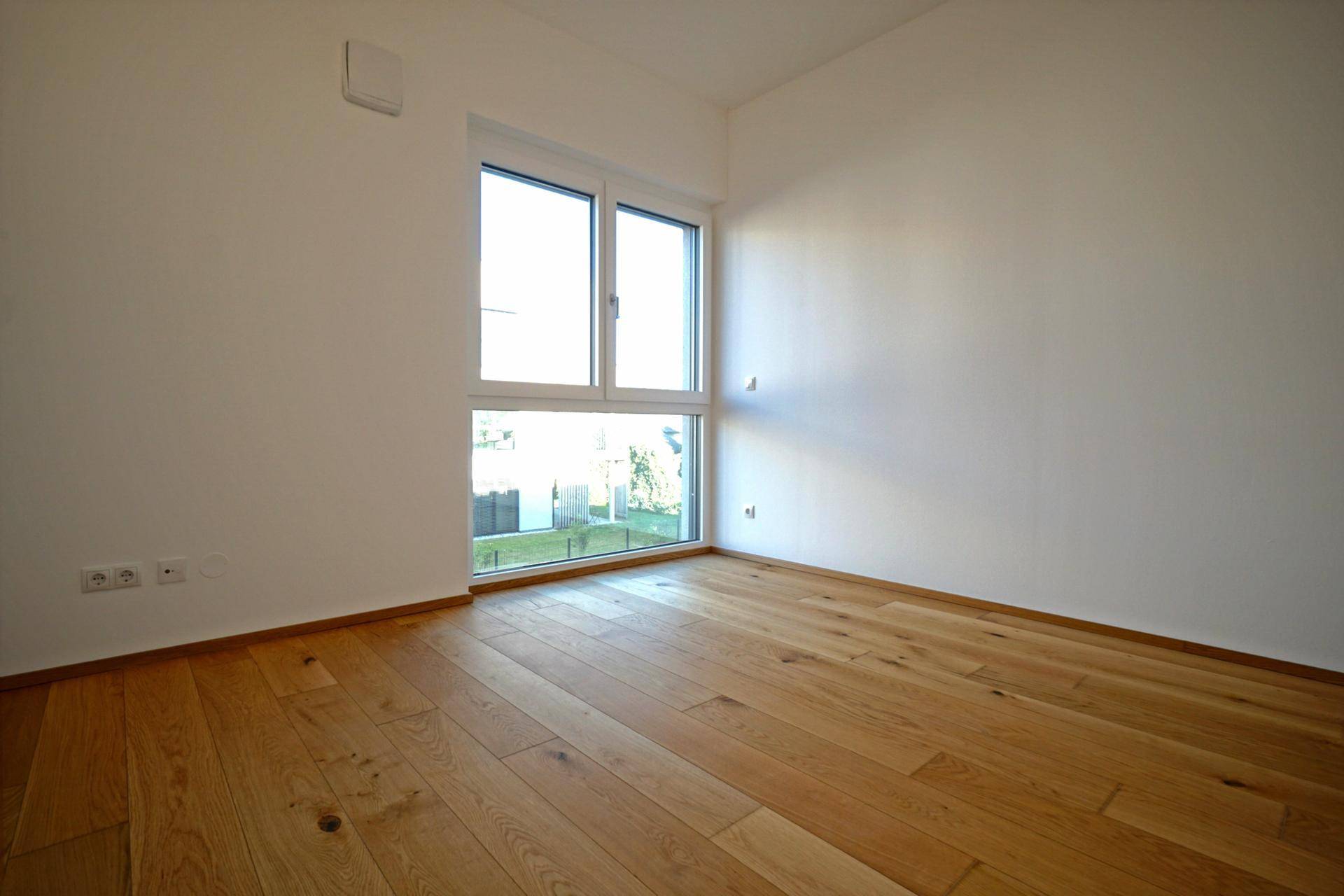 Lichtdurchflutetes Zimmer mit Holzboden und Blick ins Grüne, vielseitig nutzbar.