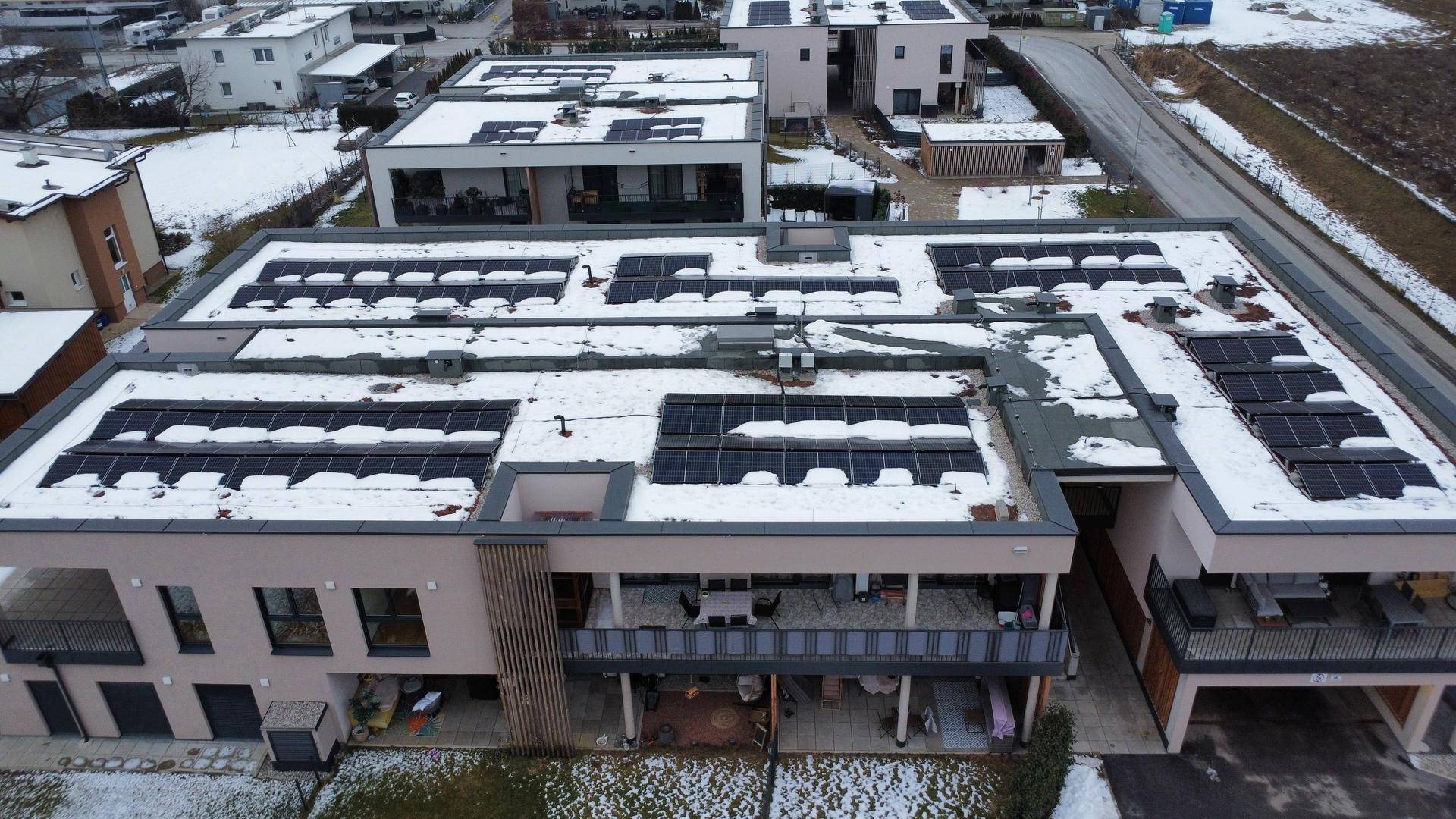 Winterliche Ansicht eines modernen Gebäudes mit Photovoltaikanlage auf dem Dach.