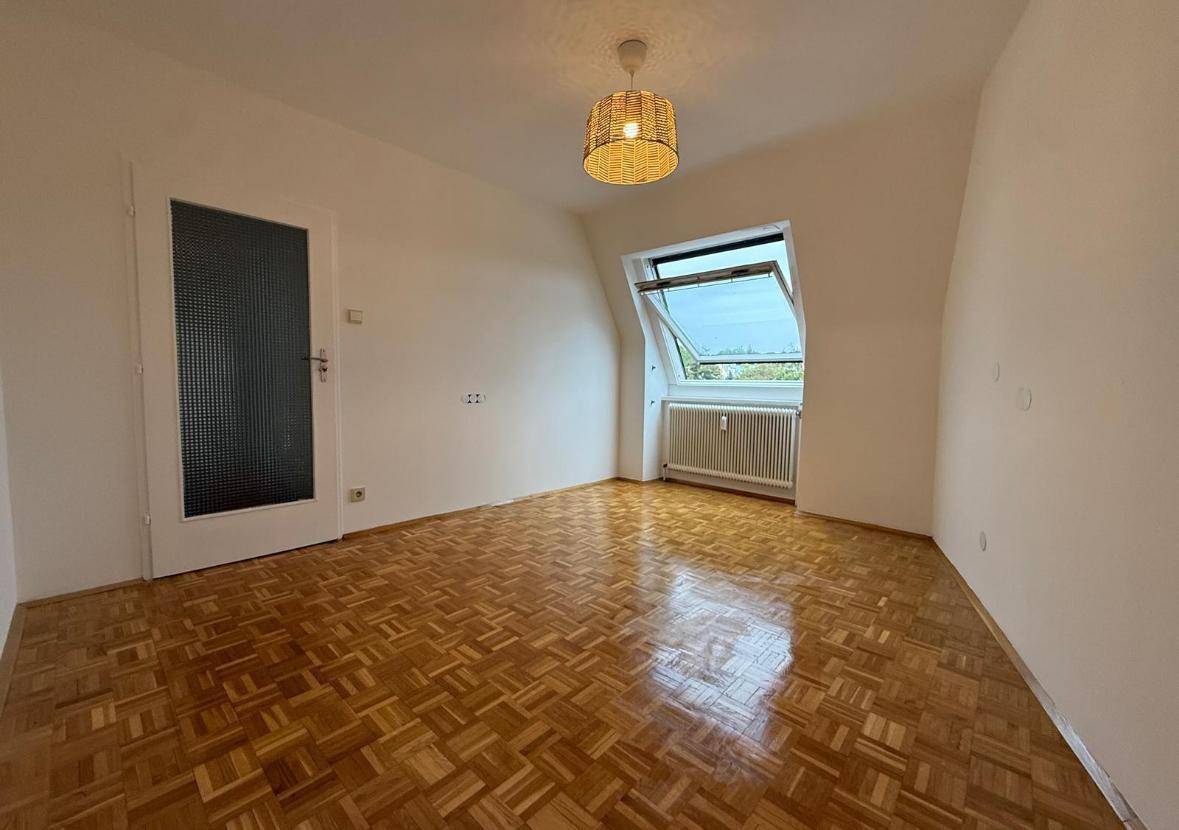 Heller Raum mit Parkettboden, Dachfenster und einer Tür mit Milchglas, bereit zur individuellen Nutzung.