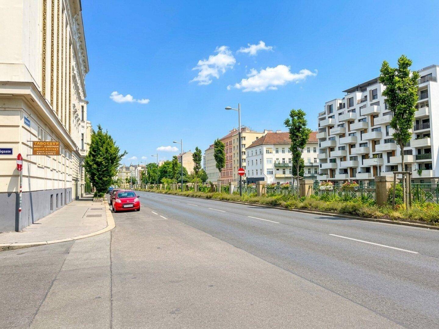Blick auf die belebte Straße mit modernen und klassischen Gebäuden unter blauem Himmel.