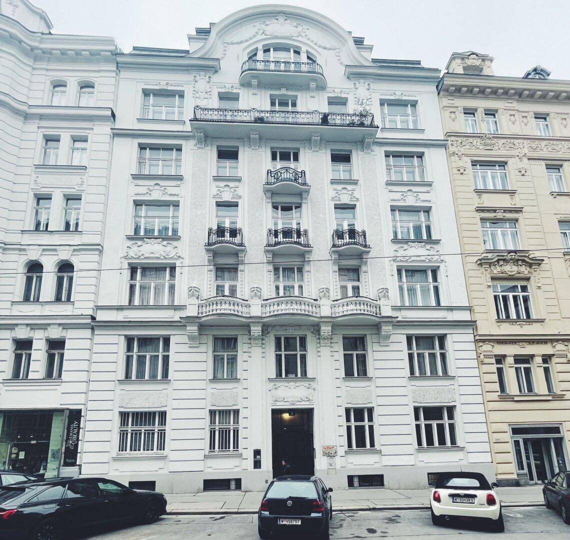 Historisches Gebäude mit reich verzierter Fassade, mehreren Balkonen und klassischen Fenstern in der Stadt.
