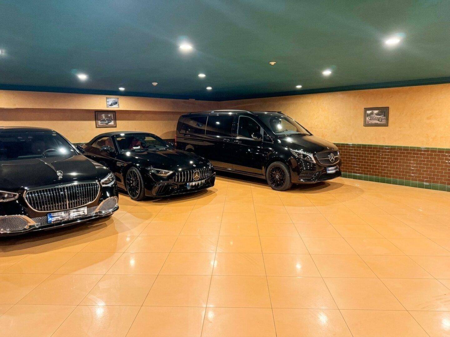 Geräumige Garage mit mehreren Luxusfahrzeugen und funktionaler Beleuchtung.