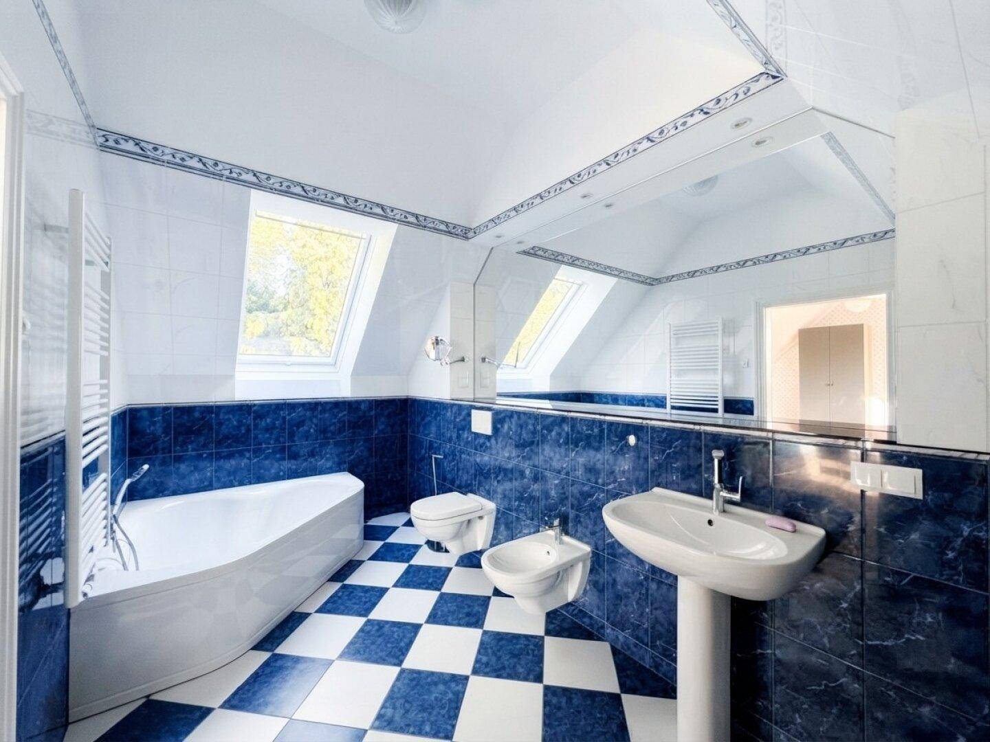 Geräumiges Badezimmer mit blauen und weißen Fliesen, Eckbadewanne und Dachfenstern.