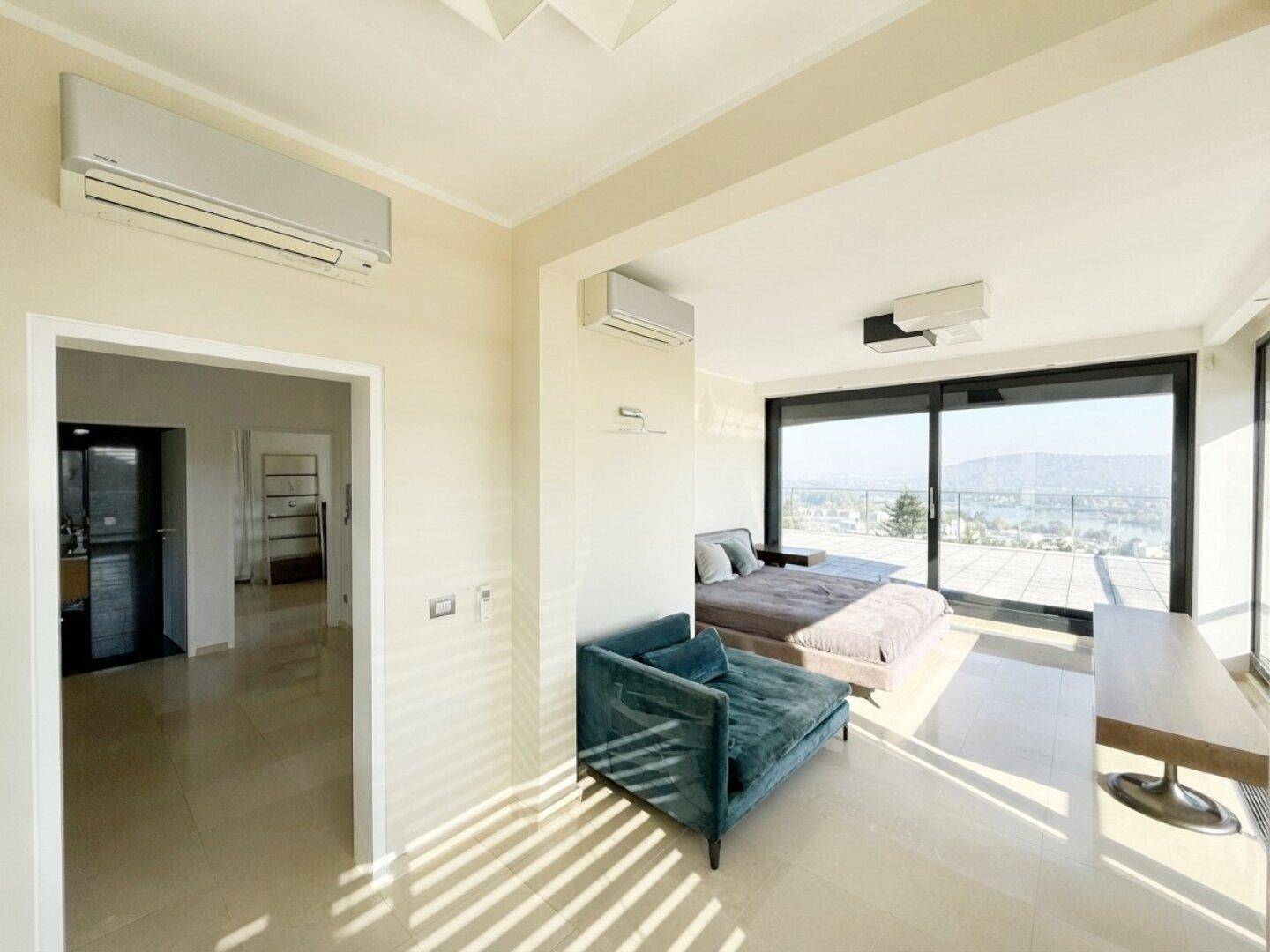 Helles Schlafzimmer mit Klimaanlage, bequemer Liege und Zugang zu einem Balkon mit Weitblick.