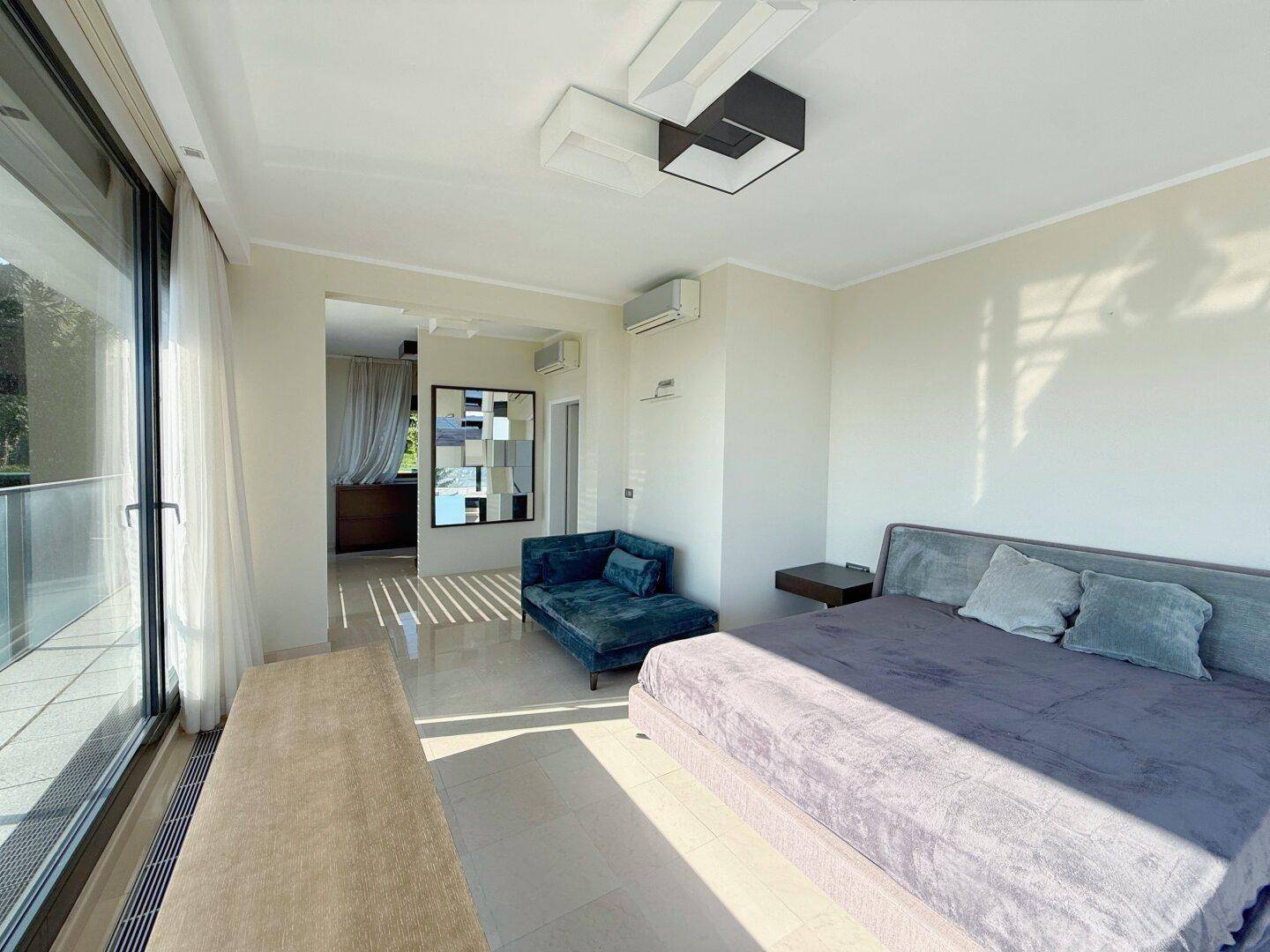 Geräumiges Schlafzimmer mit Doppelbett, Klimaanlage und Blick in den begehbaren Kleiderschrank.