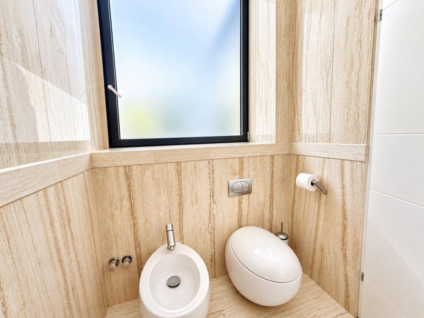 Modernes Gäste-WC mit Bidet, wandhängender Toilette und Fenster in hellen Holzoptikfliesen.