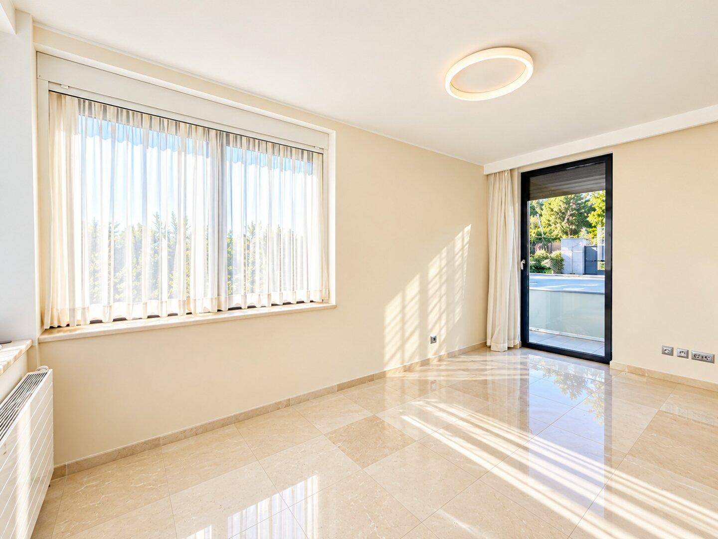 Helles Schlafzimmer mit Marmorboden und Zugang zu einem Balkon oder einer Terrasse.