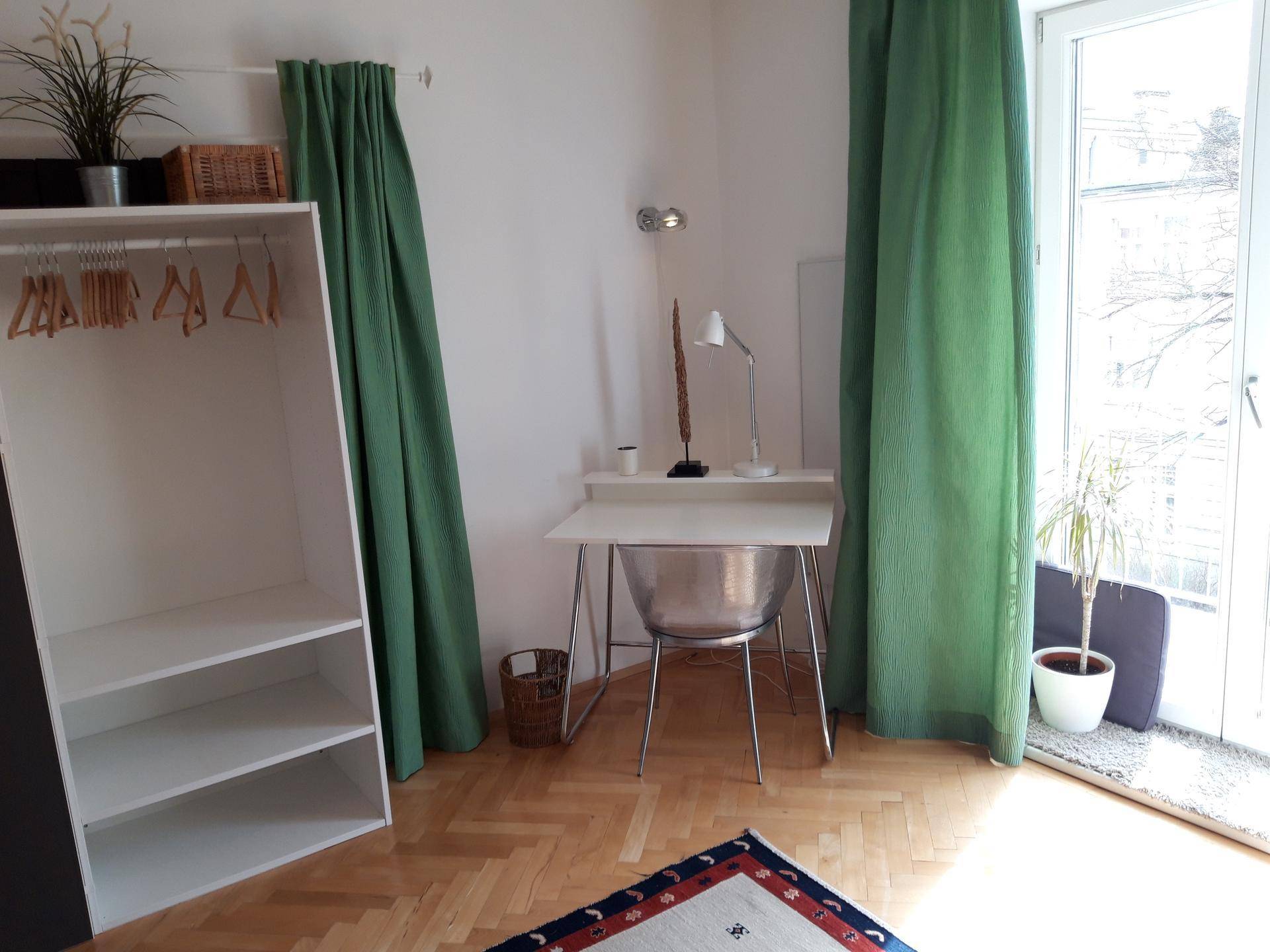 Arbeitsbereich im Schlafzimmer mit Schreibtisch, Stuhl und Zugang zu einem französischen Balkon.