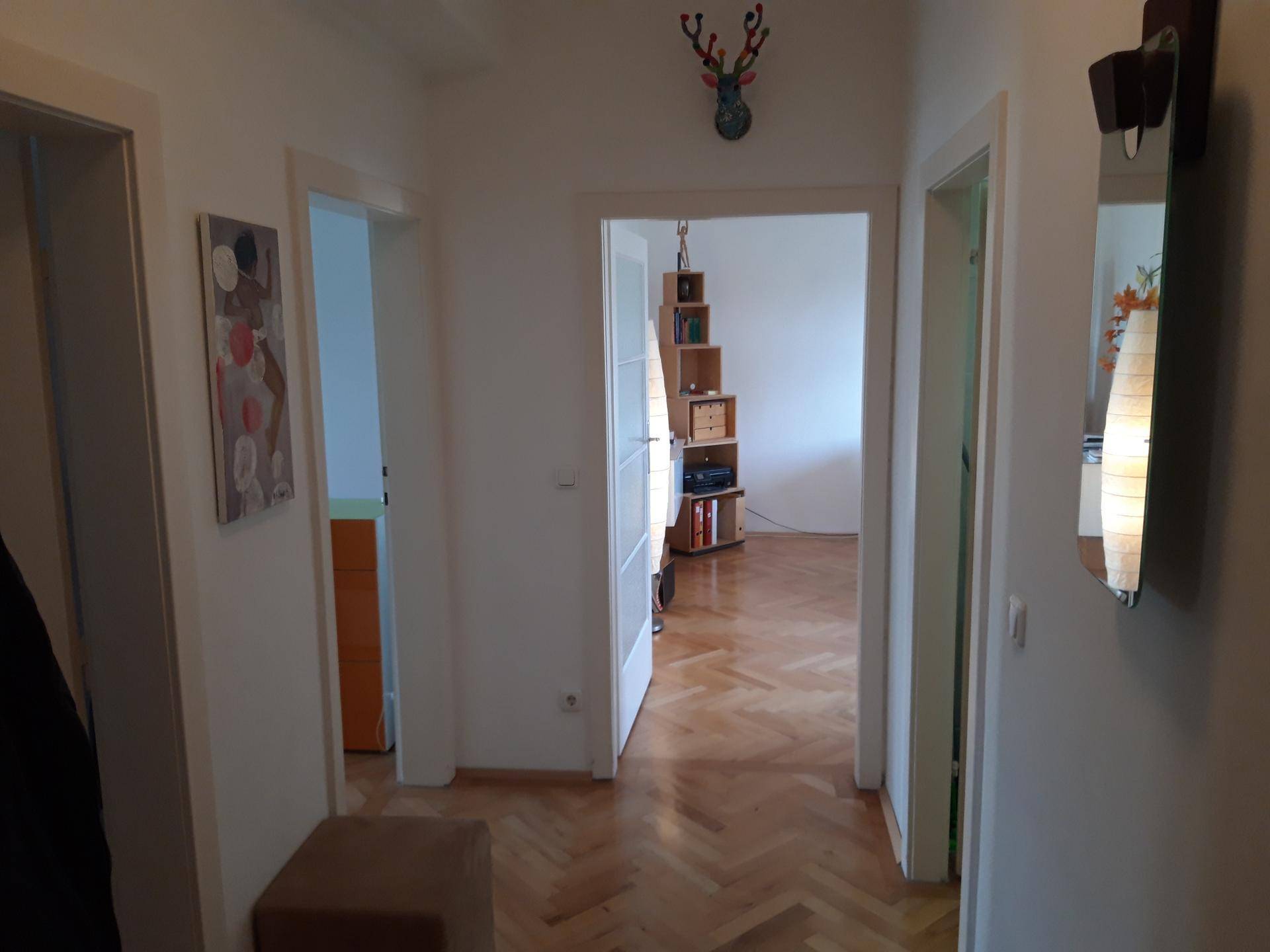 Heller Flur mit Fischgrätparkettboden und Türen zu verschiedenen Räumen.