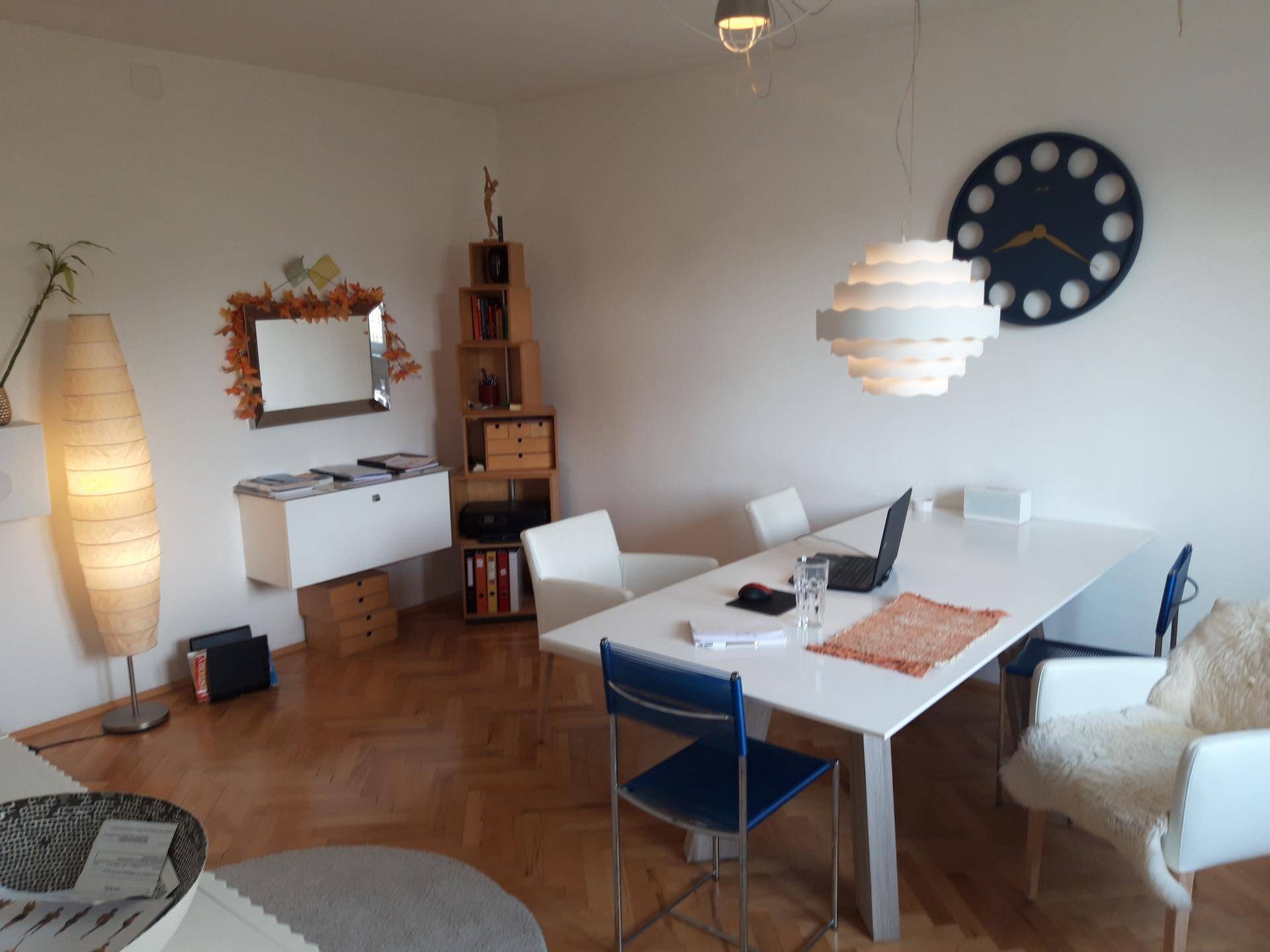 Heller Wohn- oder Essbereich mit großem Tisch, modernen Stühlen und Holzboden.