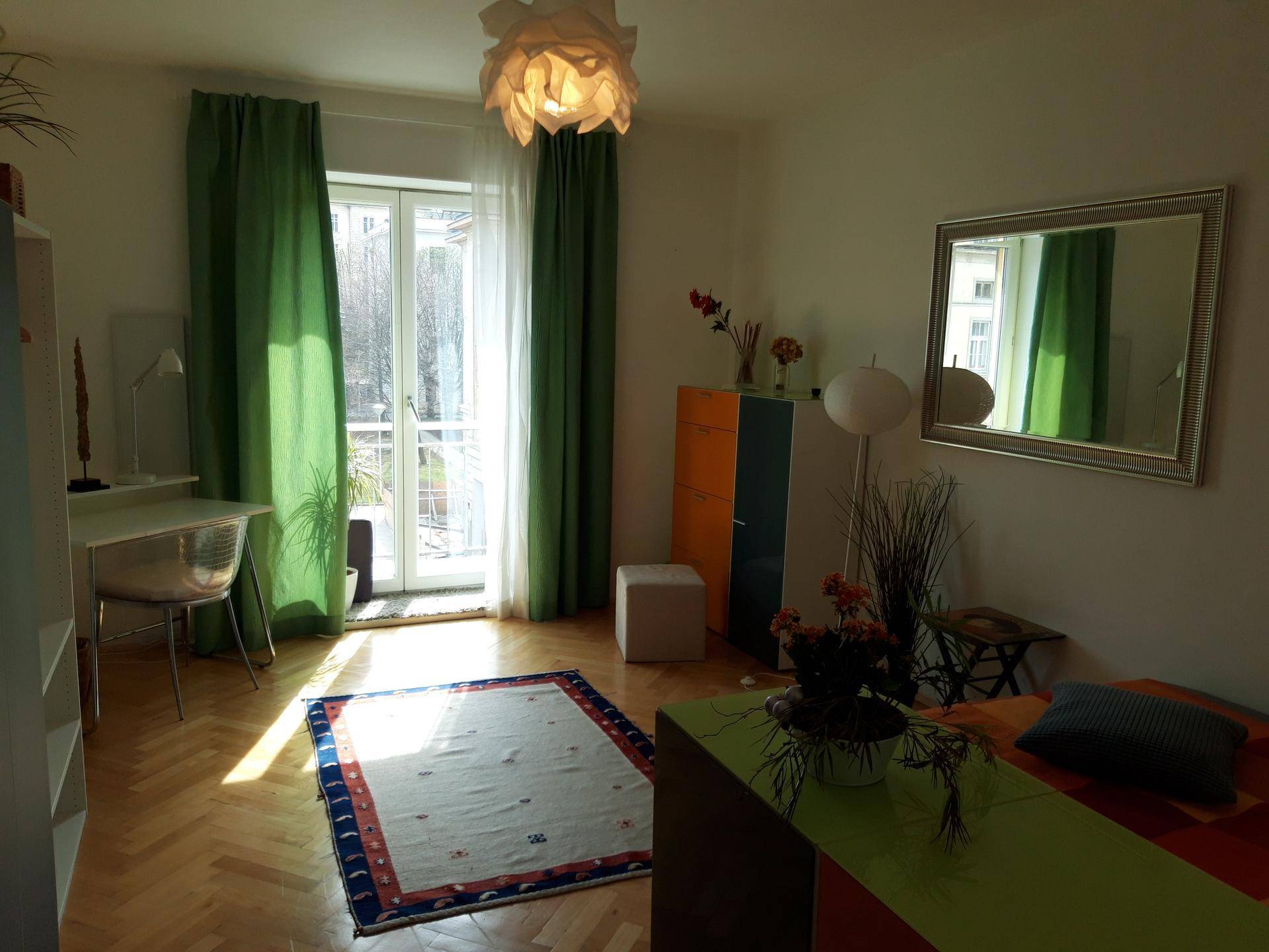 Geräumiges Schlafzimmer mit viel Tageslicht, Holzboden und farbenfrohen Akzenten.