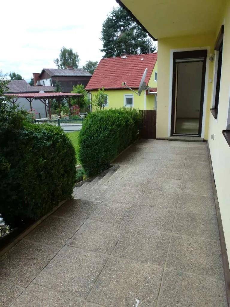 Gefliester Balkonbereich mit Hecken und Blick auf die Nachbarschaft.