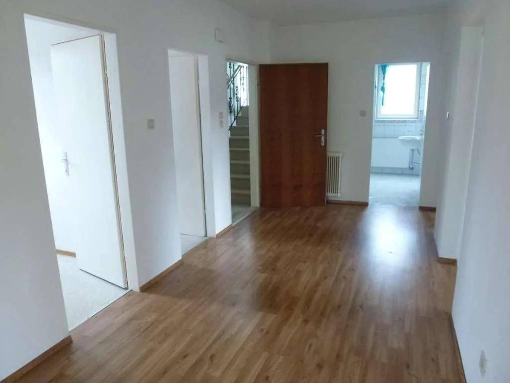 Geräumiger Flur mit Laminatboden, Treppenaufgang und Zugang zu weiteren Zimmern.