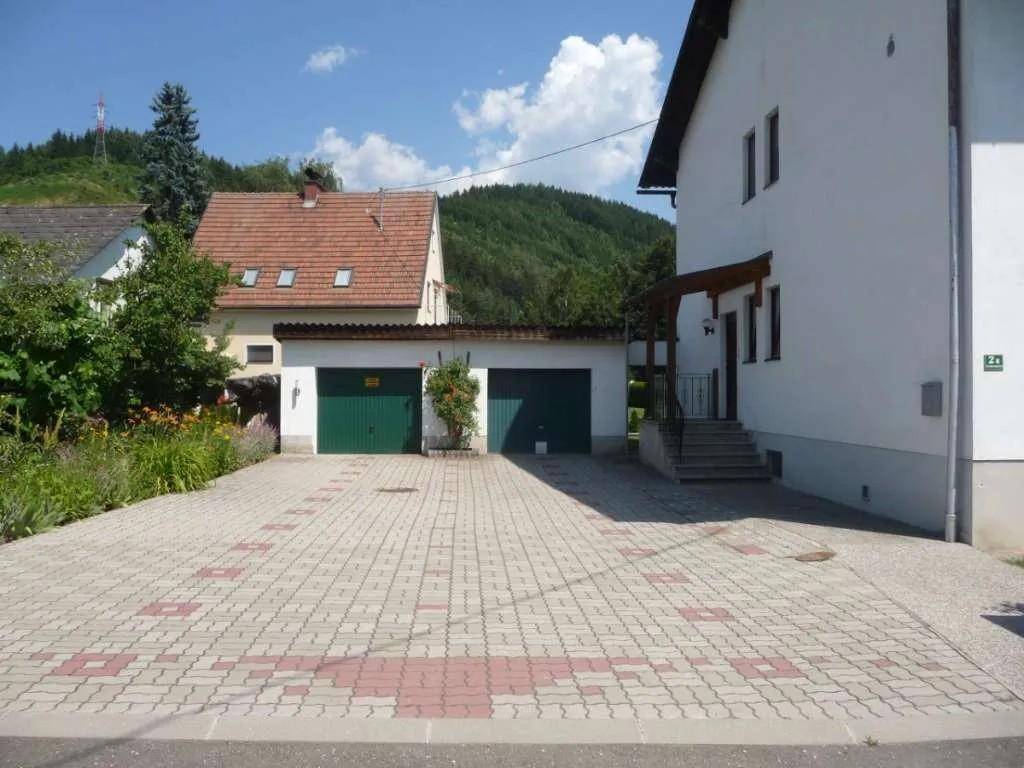 Gepflasterte Einfahrt mit zwei Garagen und Zugang zum Haus in grüner Umgebung.
