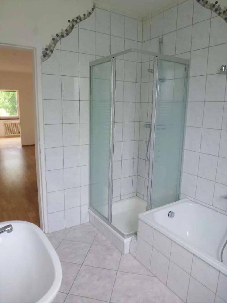 Badezimmer mit Duschkabine, Badewanne und Fliesenboden in hellem Design.