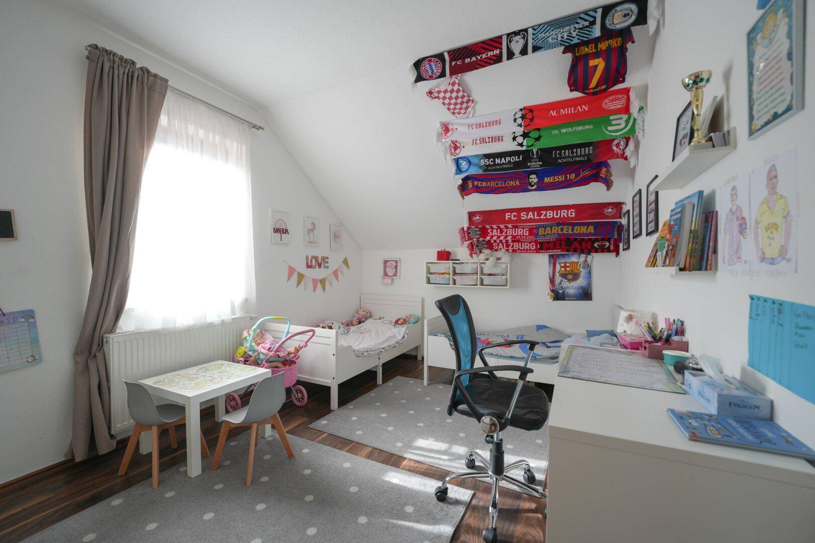 Helles Kinderzimmer im Dachgeschoss mit Spielbereich und Fenster unter der Dachschräge.