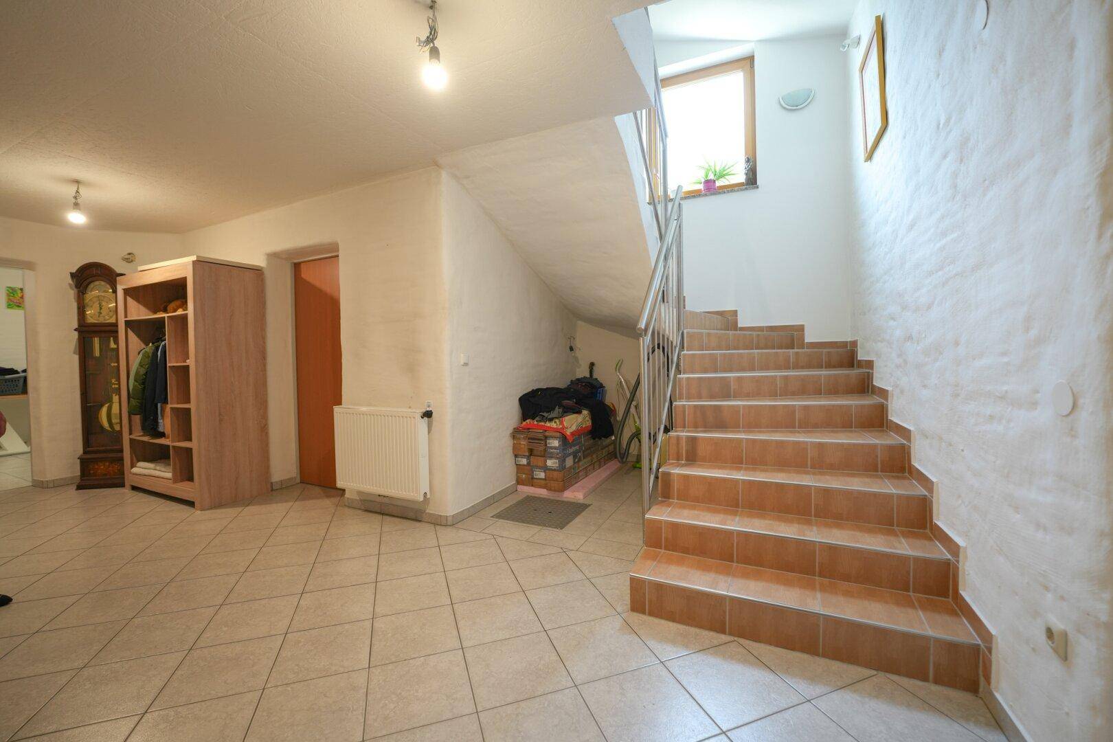 Kellerflur mit Fliesenboden, Treppe und Zugang zu weiteren Kellerräumen.