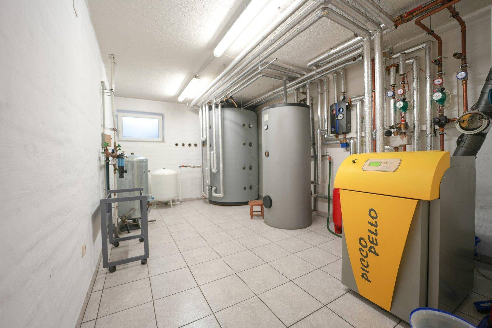 Heizungsraum im Keller mit modernen Anlagen, Warmwasserspeichern und Leitungen.