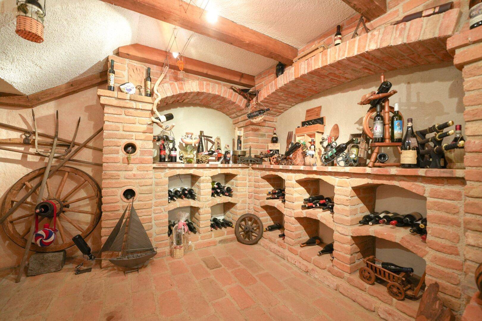 Traditioneller Weinkeller mit Ziegelregalen, Holzdekorationen und zahlreichen Weinflaschen.