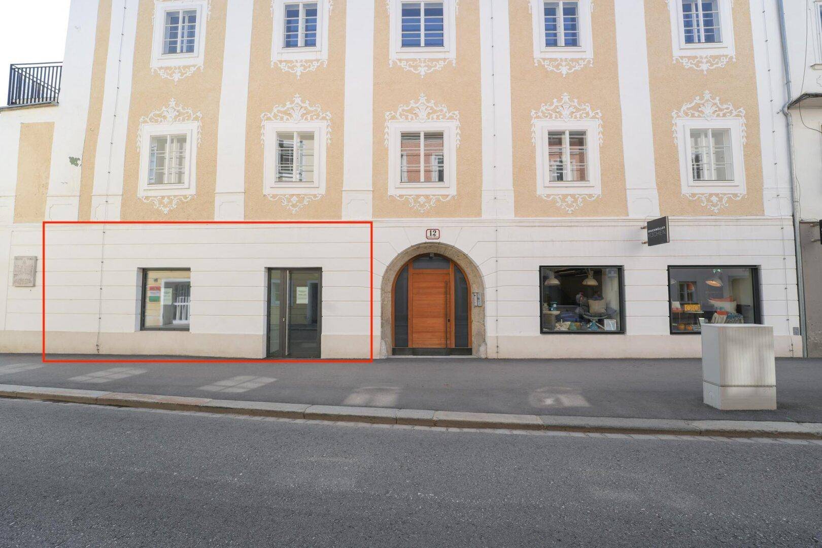 Historische Fassade eines Gebäudes mit Geschäften im Erdgeschoss und Wohnungen in den oberen Etagen.
