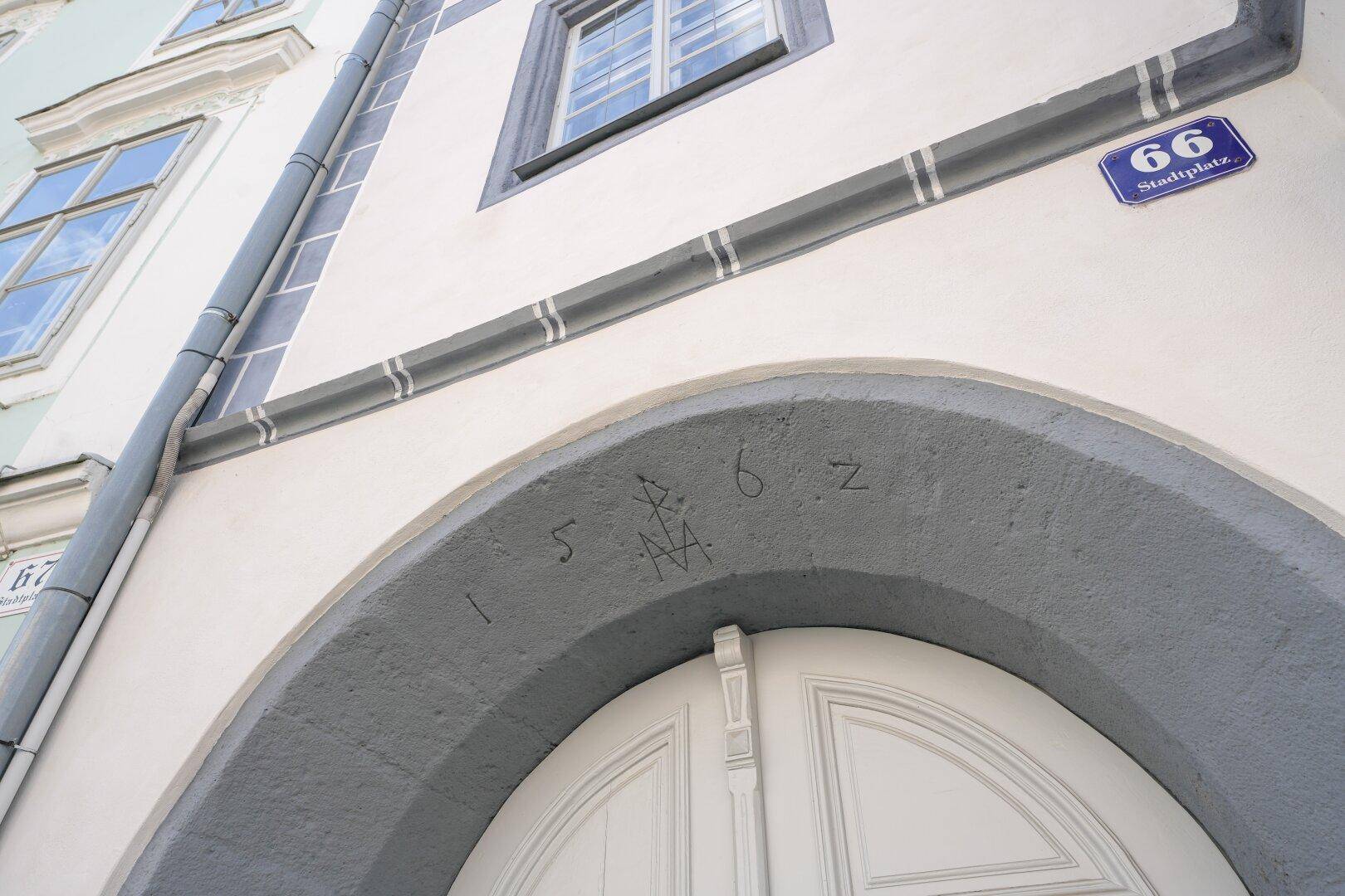 Detailansicht eines historischen Eingangs mit Steingewölbe, eingraviertem Datum 1562 und einer Hausnummer.