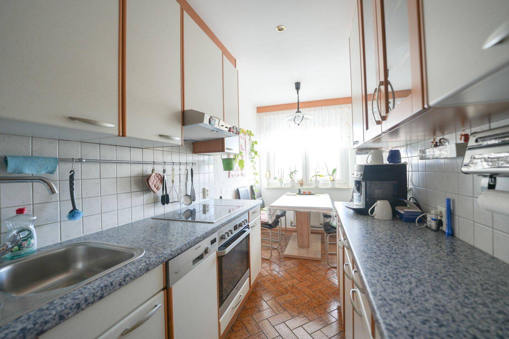 Funktionale Küche mit Einbaugeräten, Granitarbeitsplatte und Essbereich am Fenster.