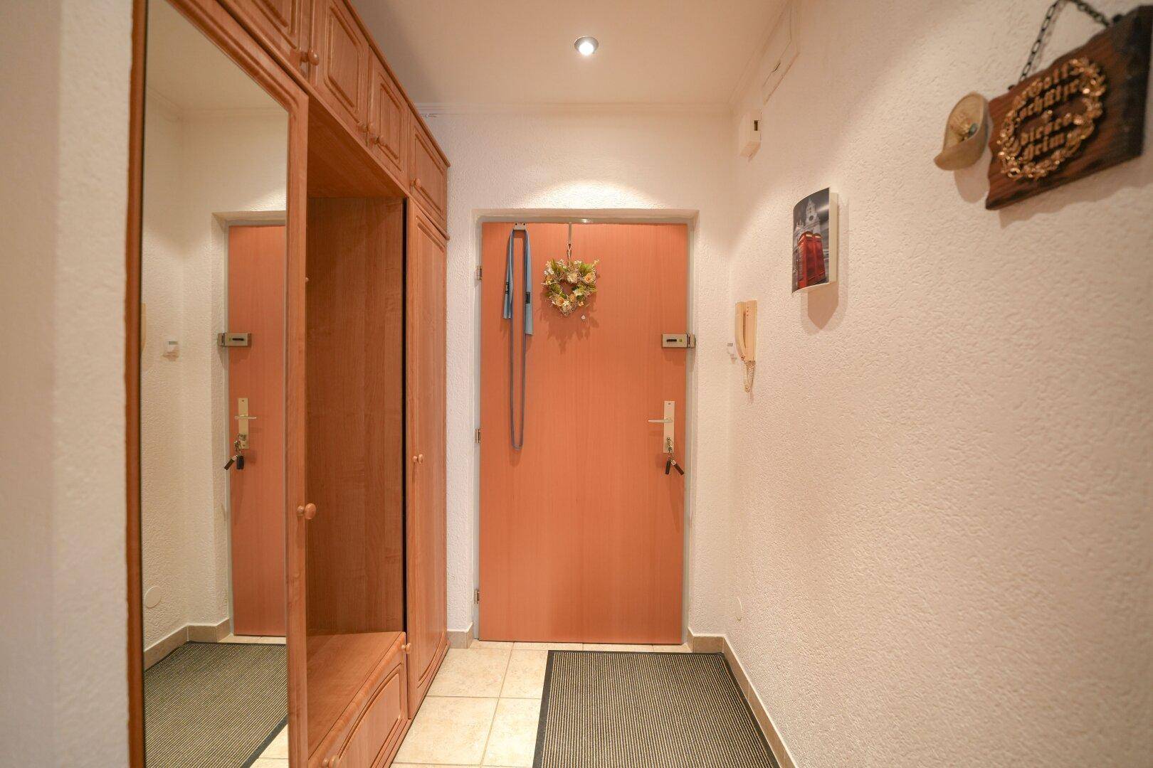 Eingangsbereich mit Fliesenboden, Garderobe und Zugang zur Wohnung.