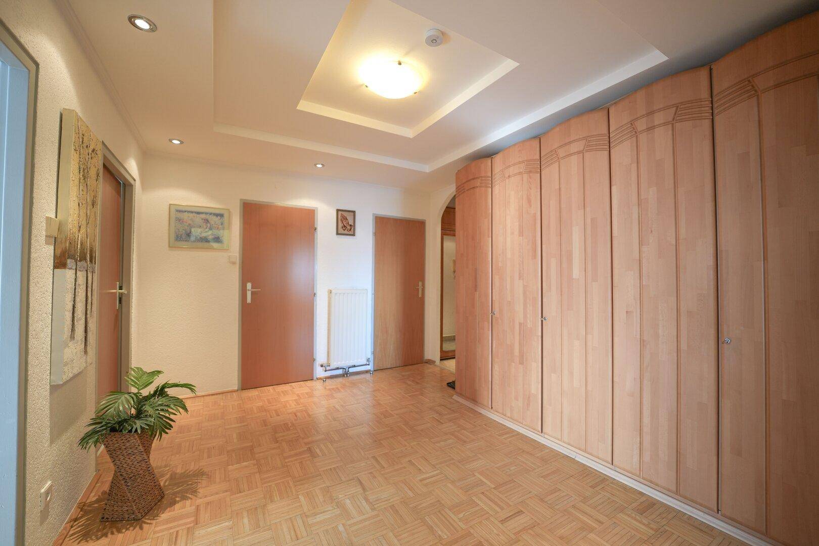 Geräumiger Flur mit Einbauschränken und Parkettboden, der viel Stauraum bietet.