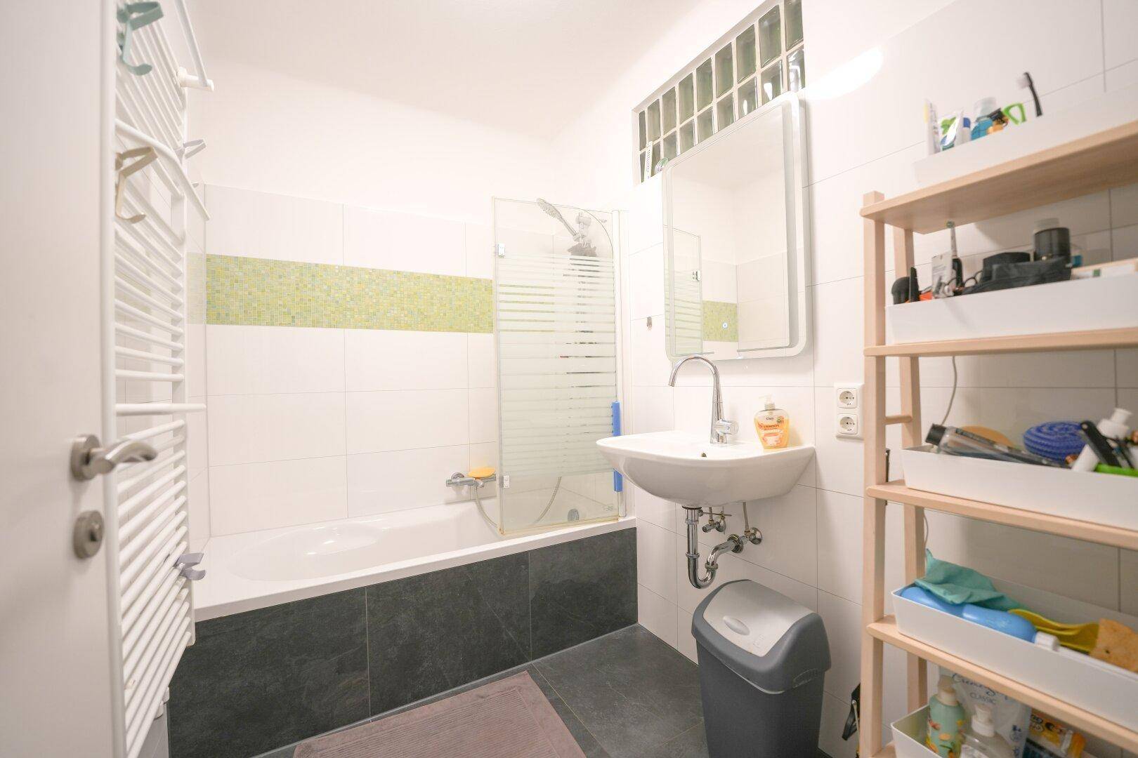 Modernes Badezimmer mit Badewanne, Duschabtrennung, Einzelwaschbecken und beheiztem Handtuchhalter.