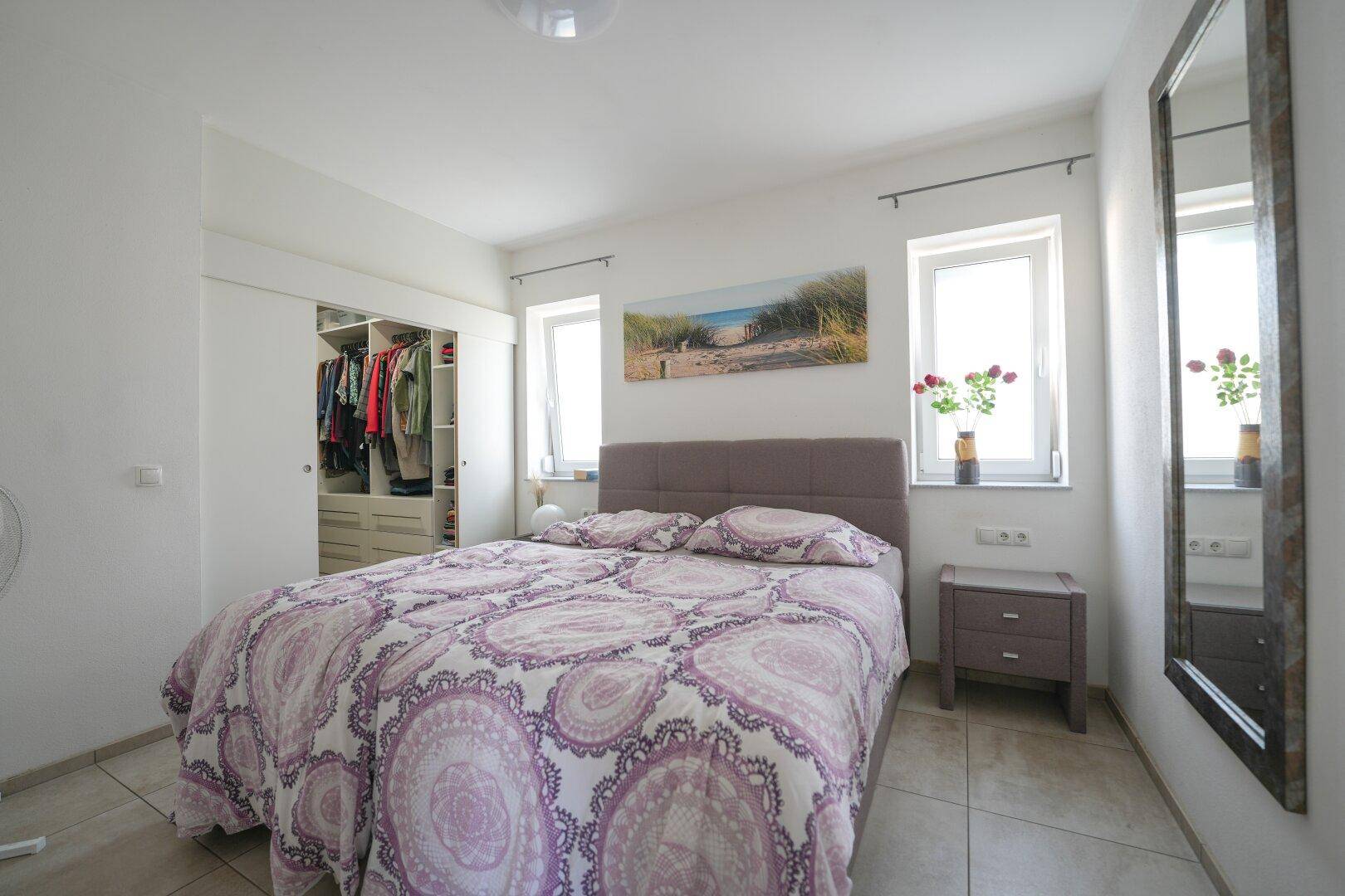 Gemütliches Schlafzimmer mit Doppelbett, integriertem Kleiderschrank und hellem Fliesenboden.