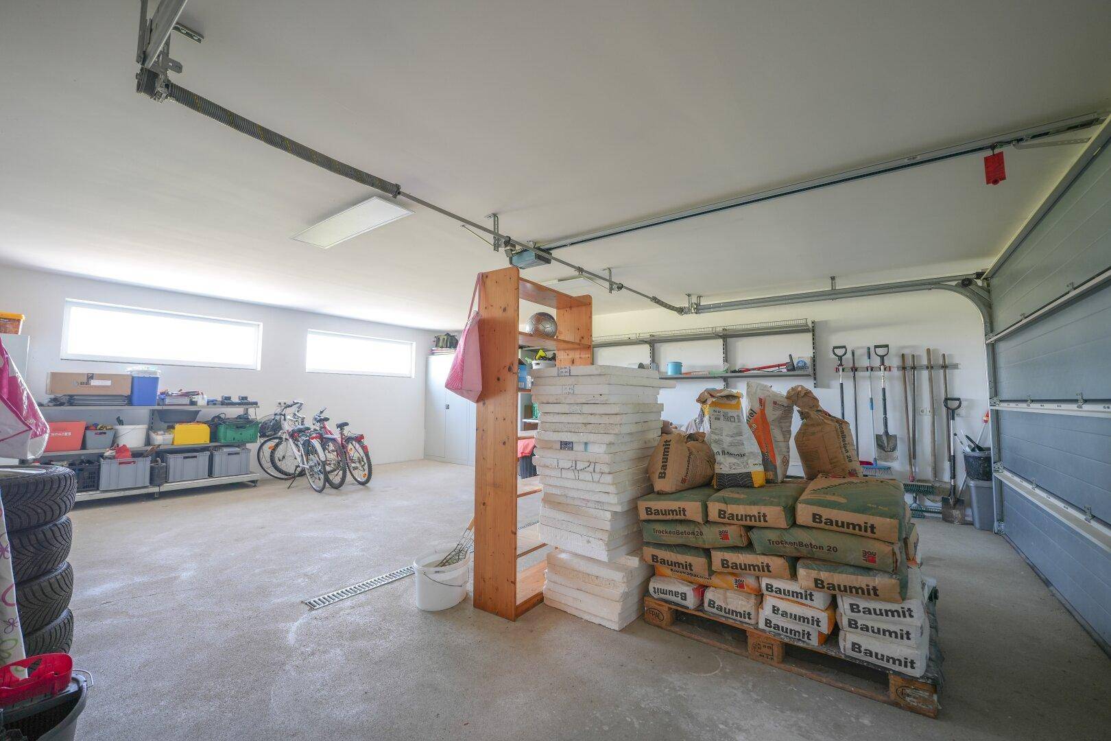Geräumige Garage mit Lagerfläche für Baumaterialien und Fahrräder.