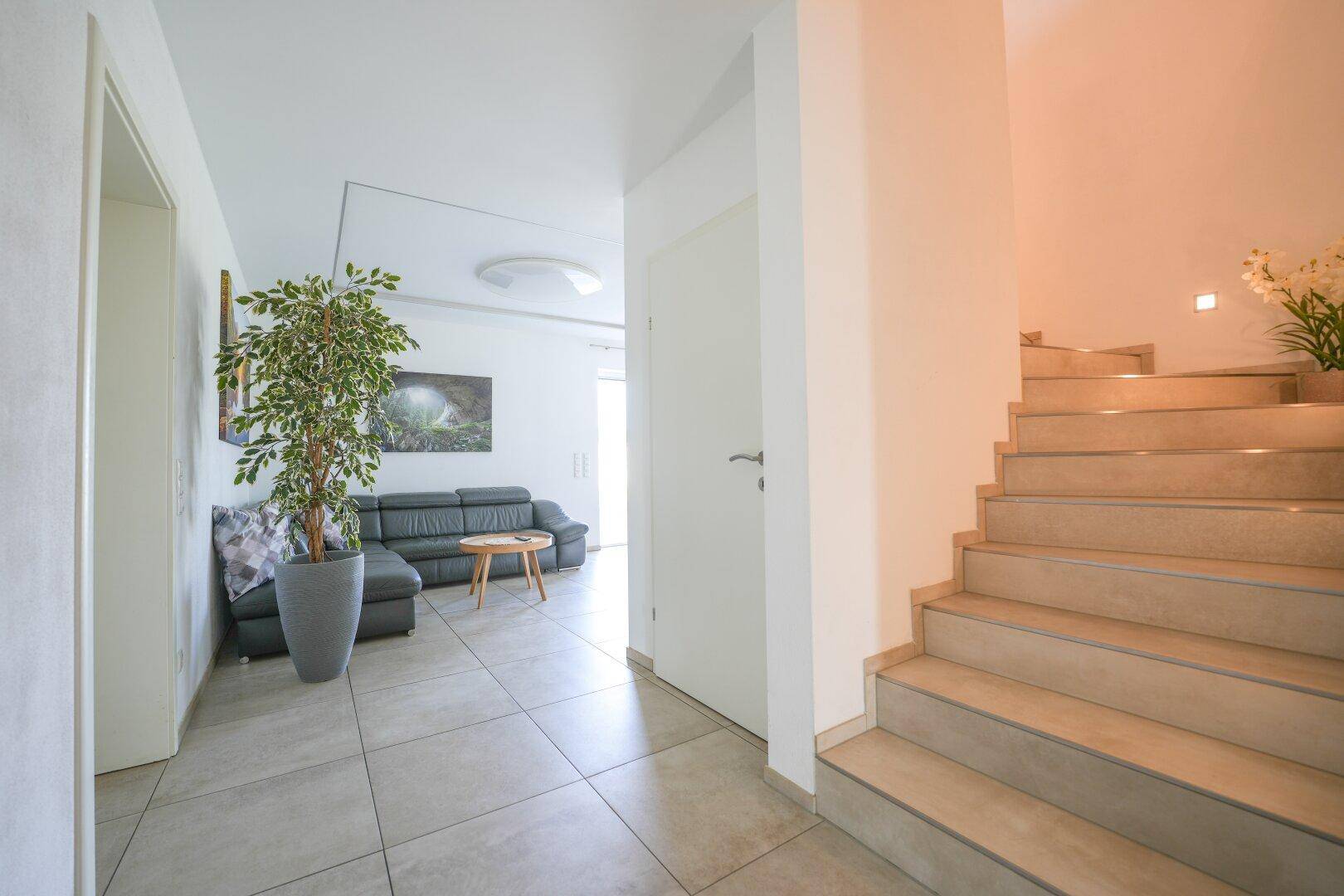 Geräumiger Flur mit hellem Fliesenboden, der zum Wohnbereich und einer Treppe führt.