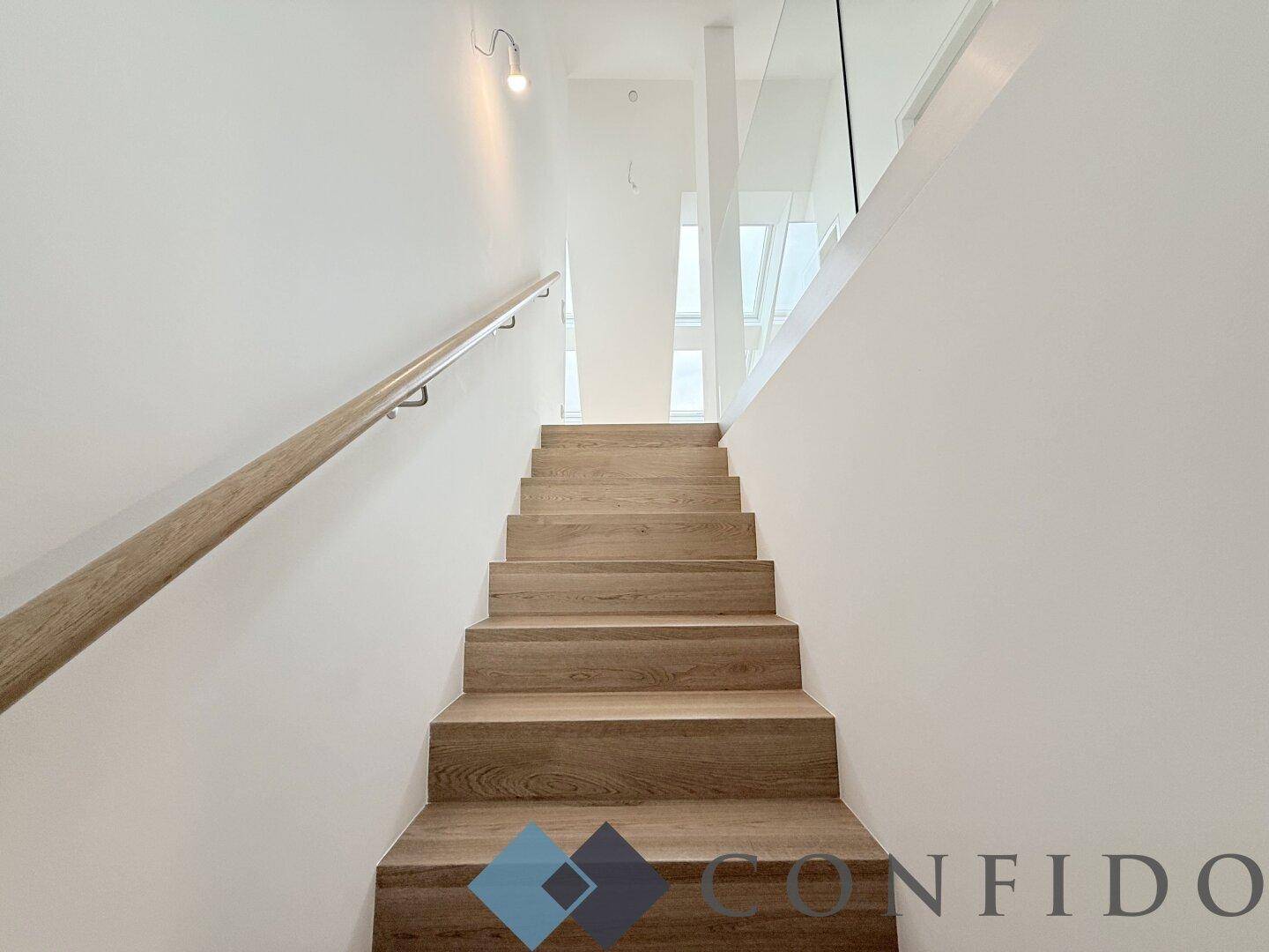 Moderner Treppenaufgang mit Holzstufen und minimalistischem Design in hellem Ambiente.