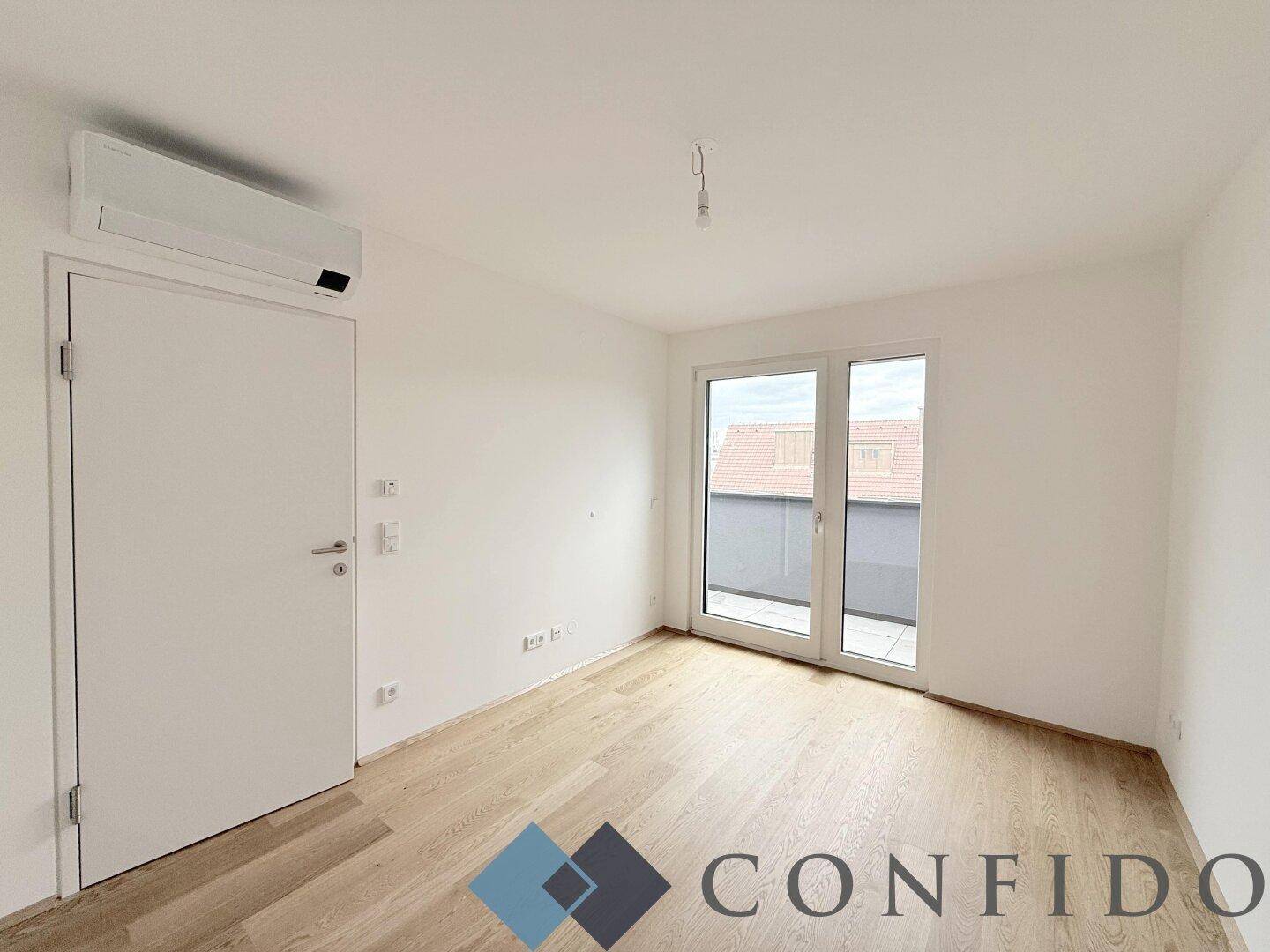 Helles Schlafzimmer mit Holzboden, Klimaanlage und Zugang zu einem kleinen Balkon.
